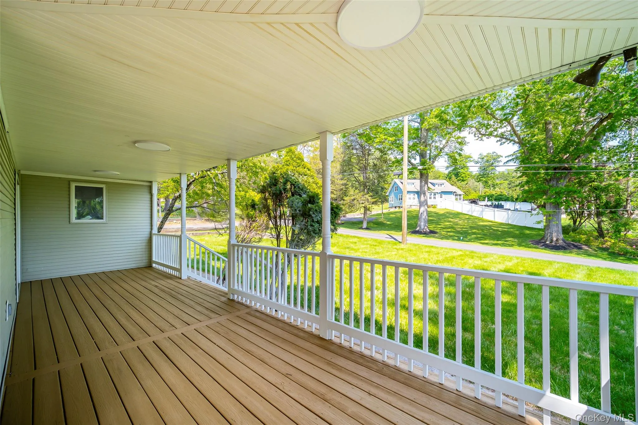 Covered porch with wood-finish decking and white railings Covered porch with wood-finish decking and white railings