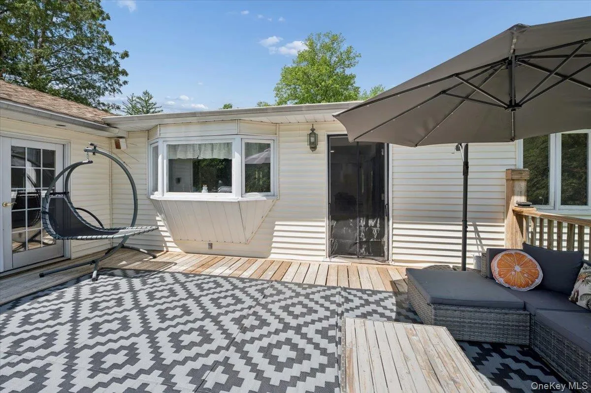 Expansive exterior deck featuring a bay window, double French doors, and a secondary entry door. Expansive exterior deck featuring a bay window, double French doors, and a secondary entry door.