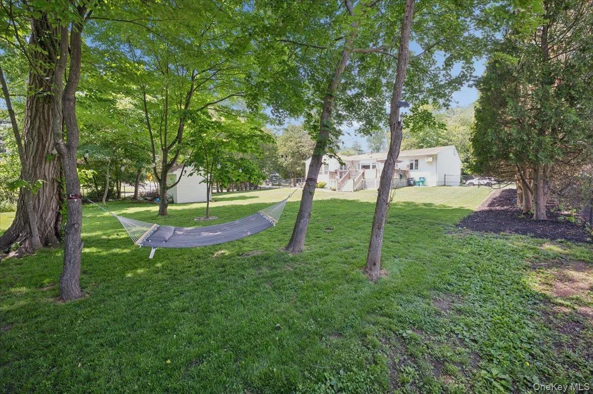 Expansive backyard featuring mature trees, a manicured lawn, and a privacy fence. Expansive backyard featuring mature trees, a manicured lawn, and a privacy fence.