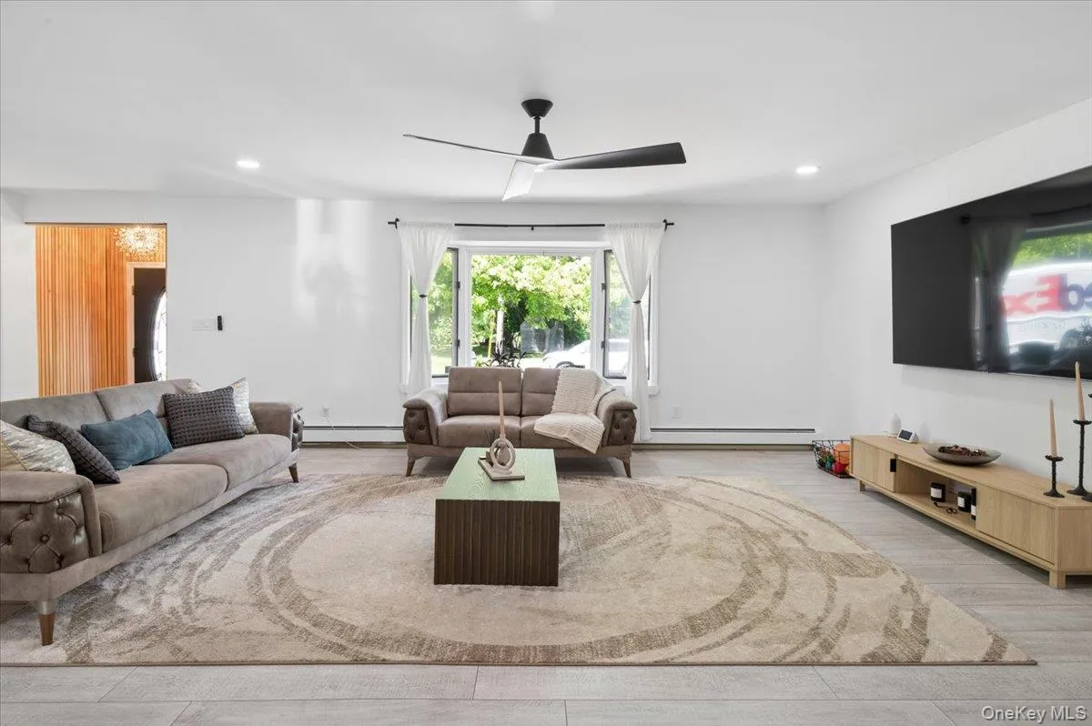 Bright living area featuring light-colored flooring, recessed lighting, a ceiling fan, and a large window. Bright living area featuring light-colored flooring, recessed lighting, a ceiling fan, and a large window.