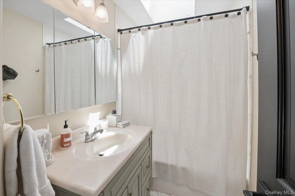 Bathroom featuring a vanity with an integrated sink, a medicine cabinet with mirrored doors, and a shower area with a curtain rod. Bathroom featuring a vanity with an integrated sink, a medicine cabinet with mirrored doors, and a shower area with a curtain rod.