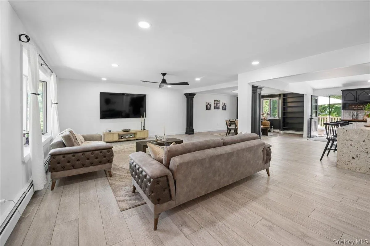 Spacious living area featuring light wood-finish flooring, recessed lighting, and a contemporary ceiling fan. Spacious living area featuring light wood-finish flooring, recessed lighting, and a contemporary ceiling fan.