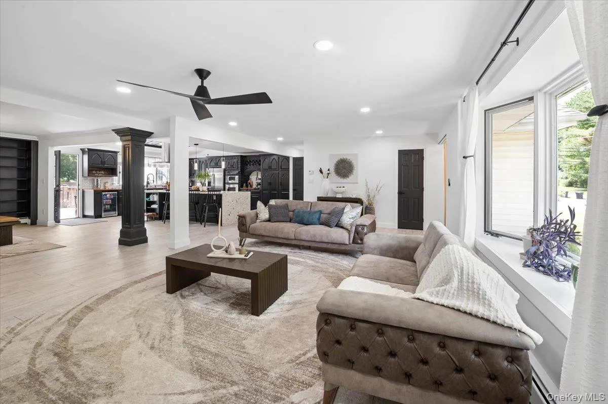 Open-concept living area with light wood-finish flooring, recessed lighting, and a modern ceiling fan. Open-concept living area with light wood-finish flooring, recessed lighting, and a modern ceiling fan.