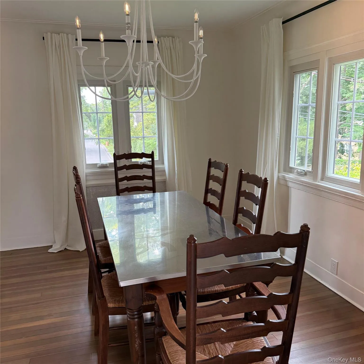 Hardwood flooring, white window treatments, a multi-pane window, and a candelabra-style chandelier Hardwood flooring, white window treatments, a multi-pane window, and a candelabra-style chandelier