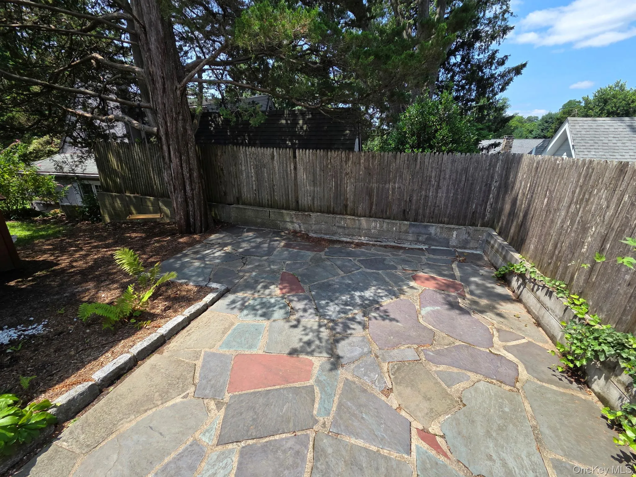 Flagstone patio with a natural wood fence and mature tree Flagstone patio with a natural wood fence and mature tree
