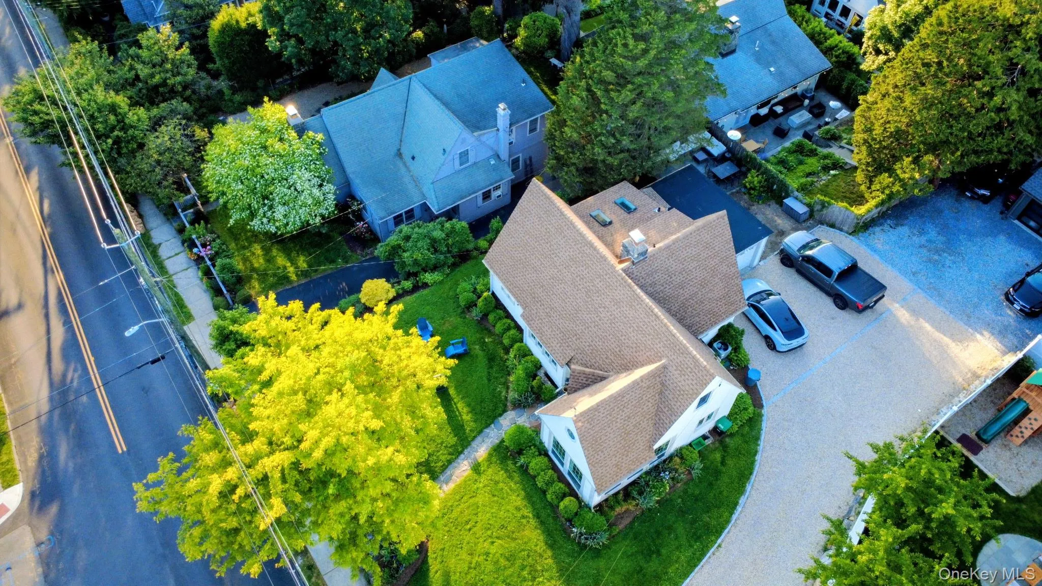 Expansive gravel driveway, manicured lawn, lush trees, and a well-maintained exterior Expansive gravel driveway, manicured lawn, lush trees, and a well-maintained exterior