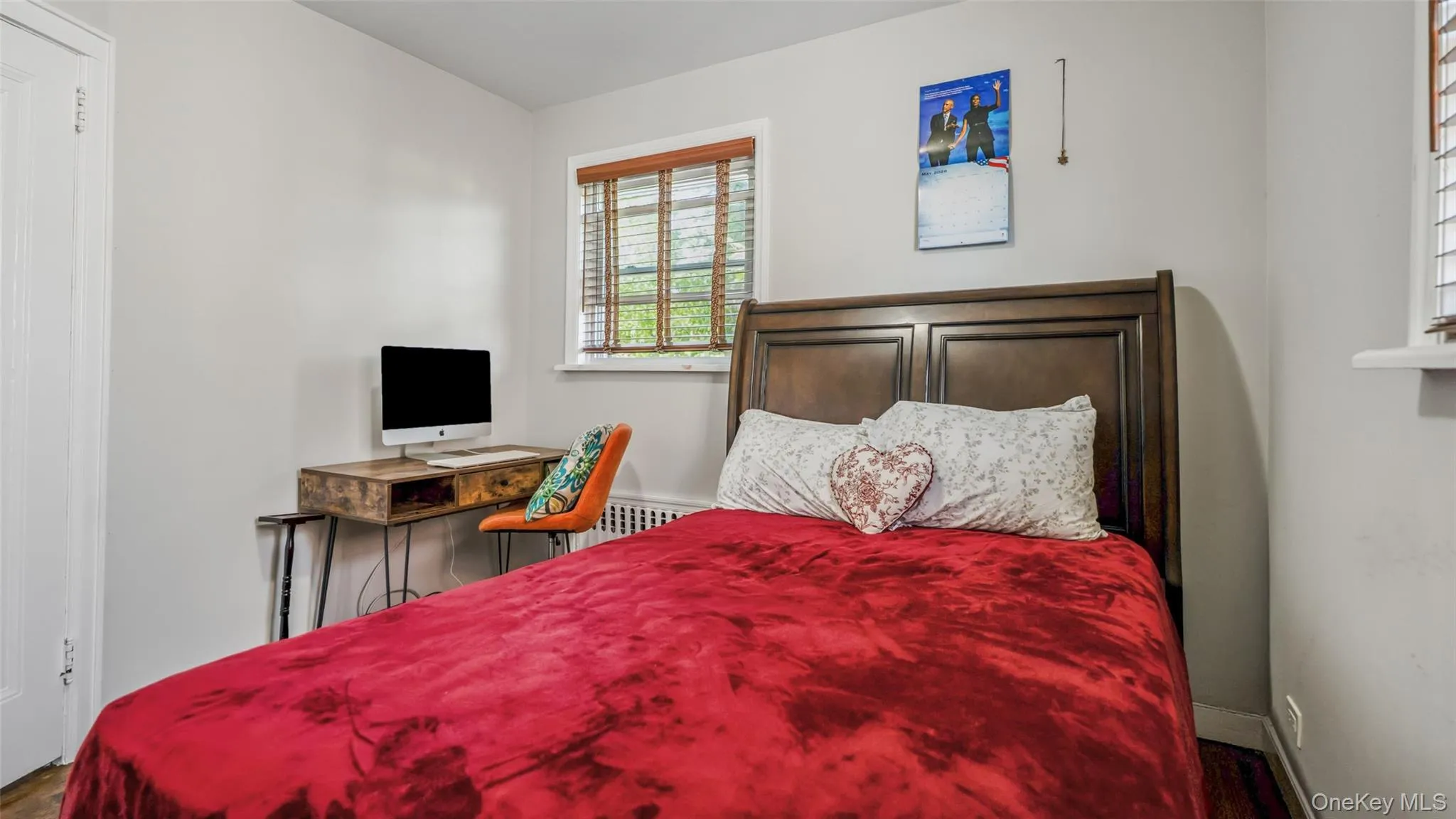 Bedroom featuring a dark wood-finish headboard, two windows with wood-finish blinds, and light-toned walls Bedroom featuring a dark wood-finish headboard, two windows with wood-finish blinds, and light-toned walls