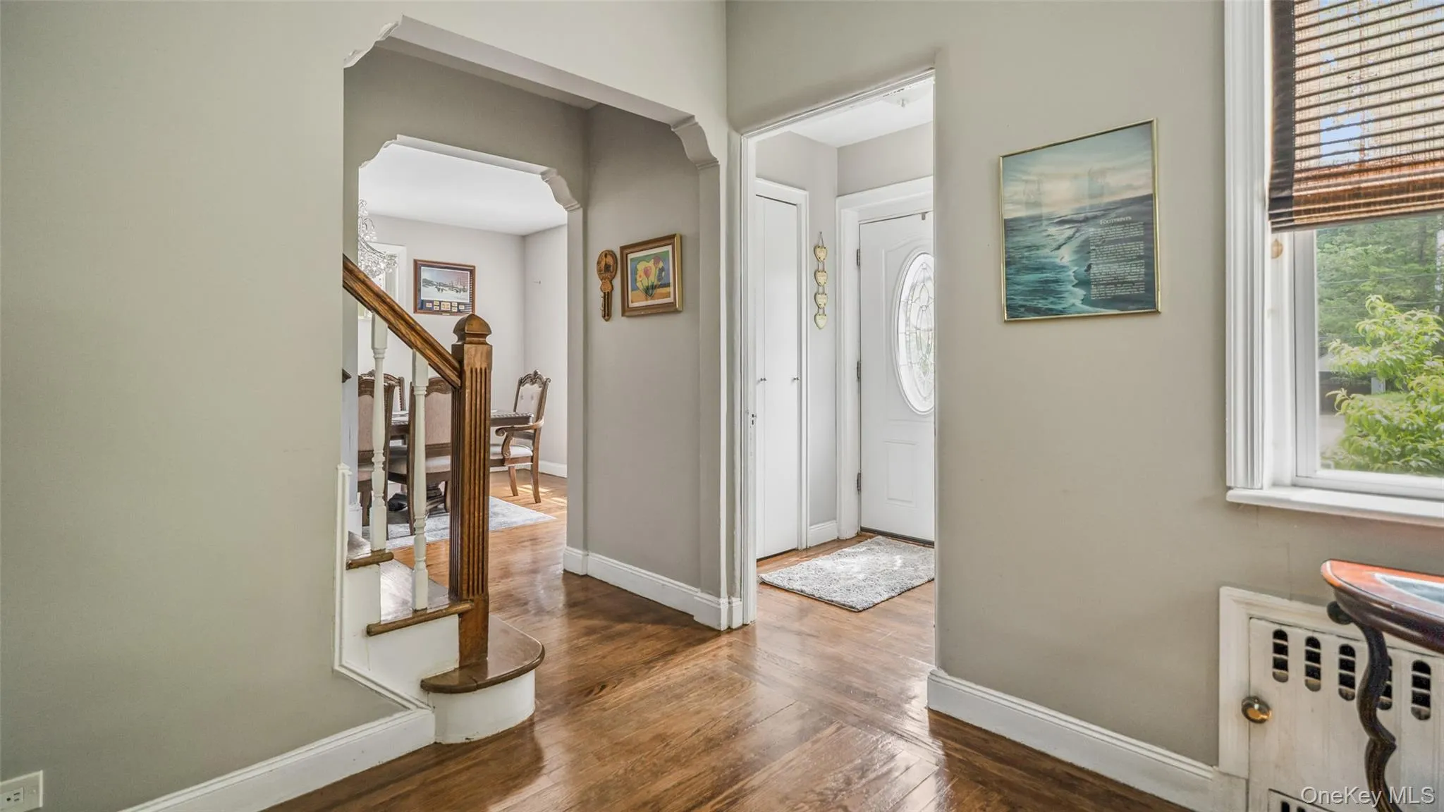 Hardwood flooring throughout the entry, staircase with wood newel post and balusters, and arched doorways Hardwood flooring throughout the entry, staircase with wood newel post and balusters, and arched doorways