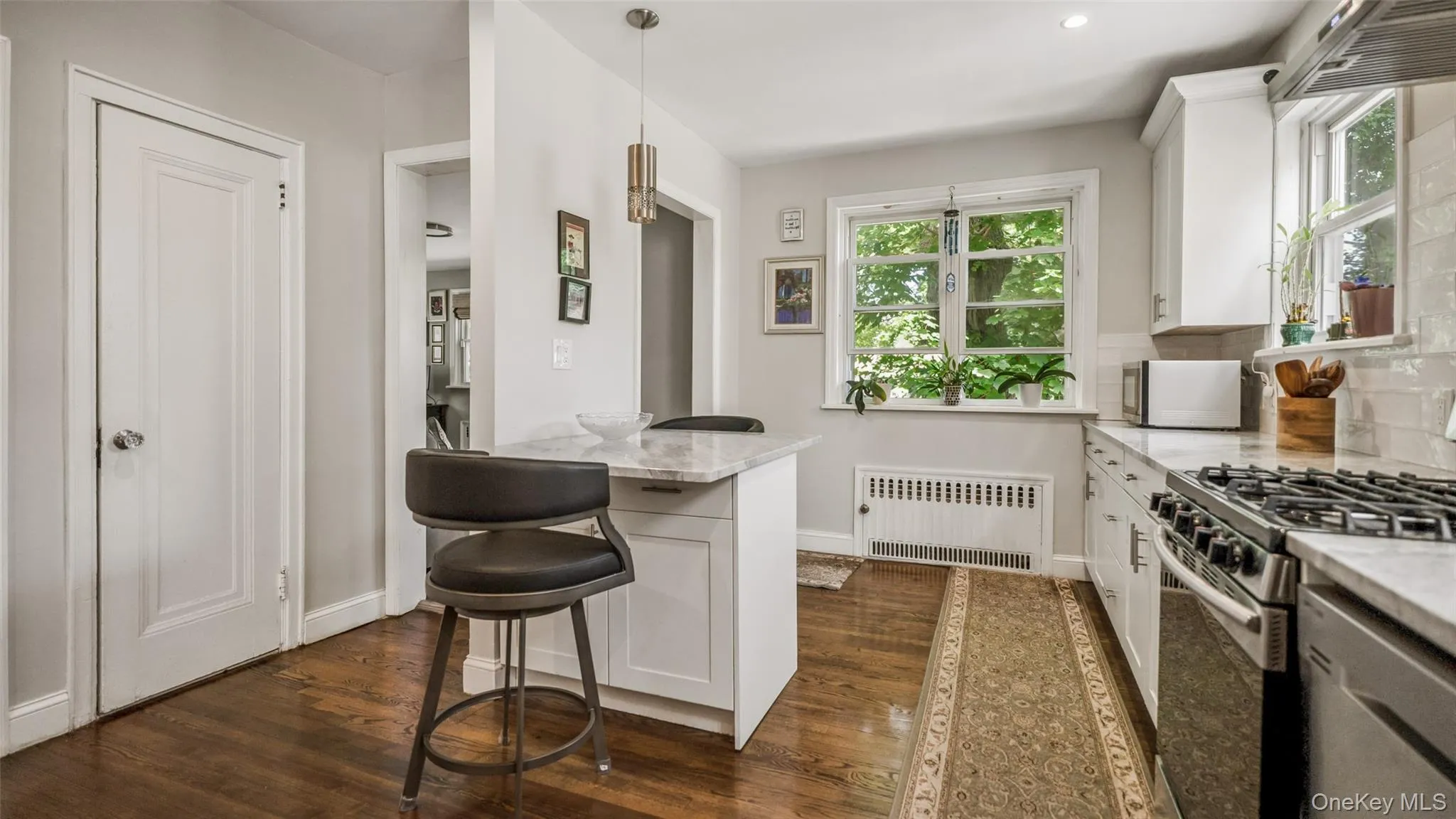 Contemporary kitchen featuring shaker-style cabinetry, stainless steel appliances, marble-finish countertops, and wood-finish flooring Contemporary kitchen featuring shaker-style cabinetry, stainless steel appliances, marble-finish countertops, and wood-finish flooring