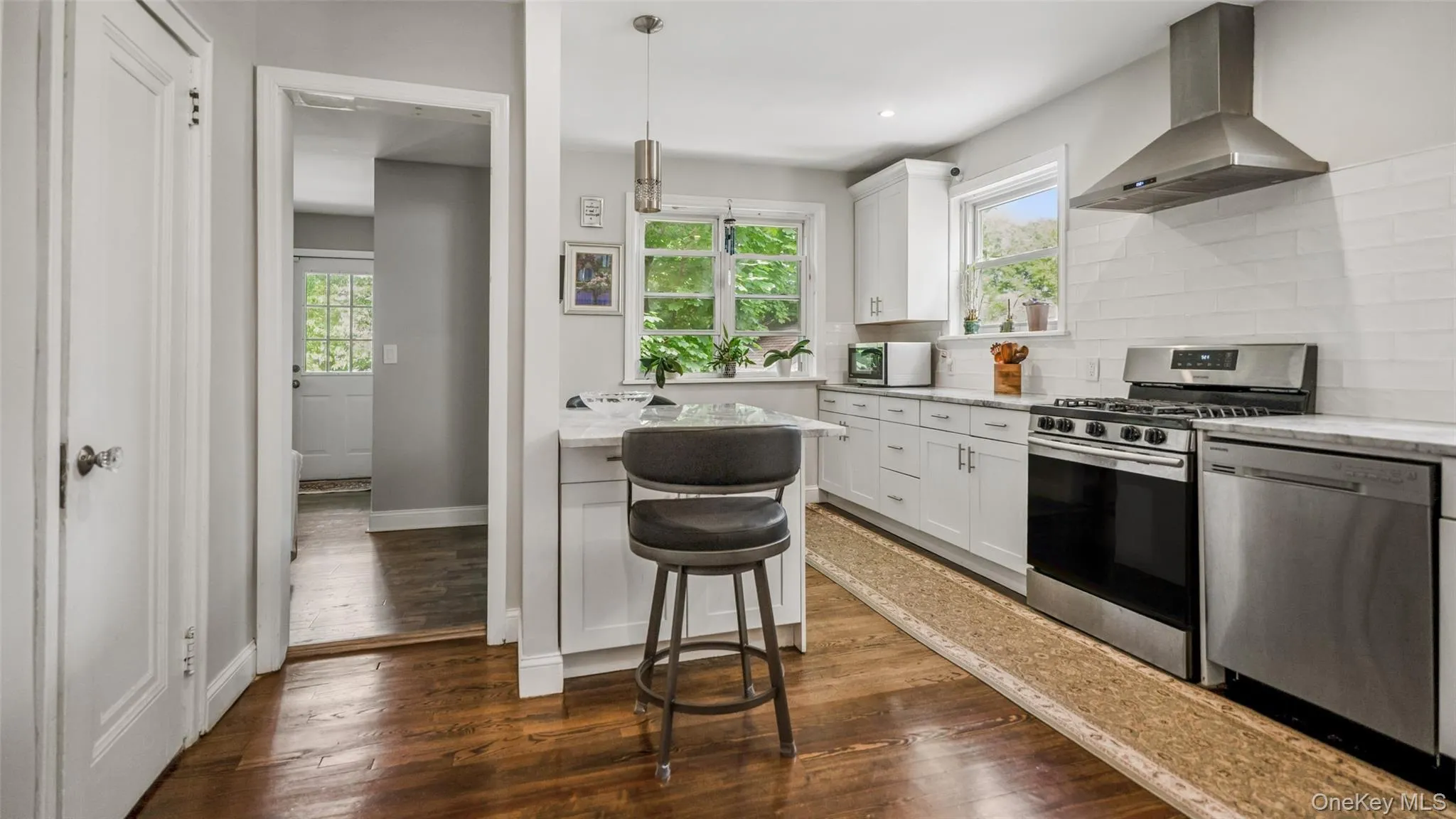 Modern kitchen featuring white shaker cabinetry, stainless steel appliances, a subway tile backsplash, and light-toned countertops Modern kitchen featuring white shaker cabinetry, stainless steel appliances, a subway tile backsplash, and light-toned countertops