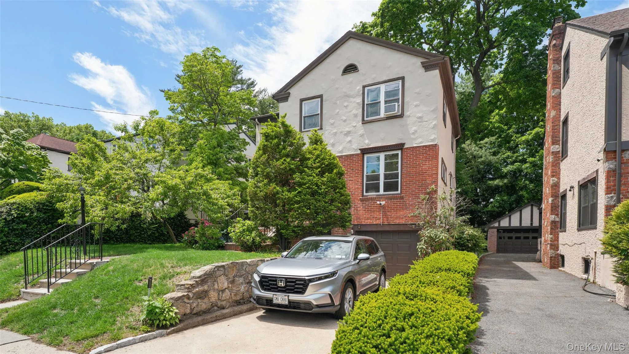 Two-story stucco and brick exterior featuring a single-car garage and additional driveway parking Two-story stucco and brick exterior featuring a single-car garage and additional driveway parking