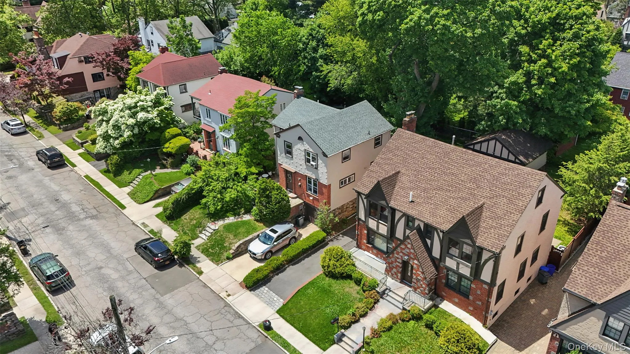 Tudor-style residence featuring brick accents, dark timbering, and a brown shingle roof Tudor-style residence featuring brick accents, dark timbering, and a brown shingle roof