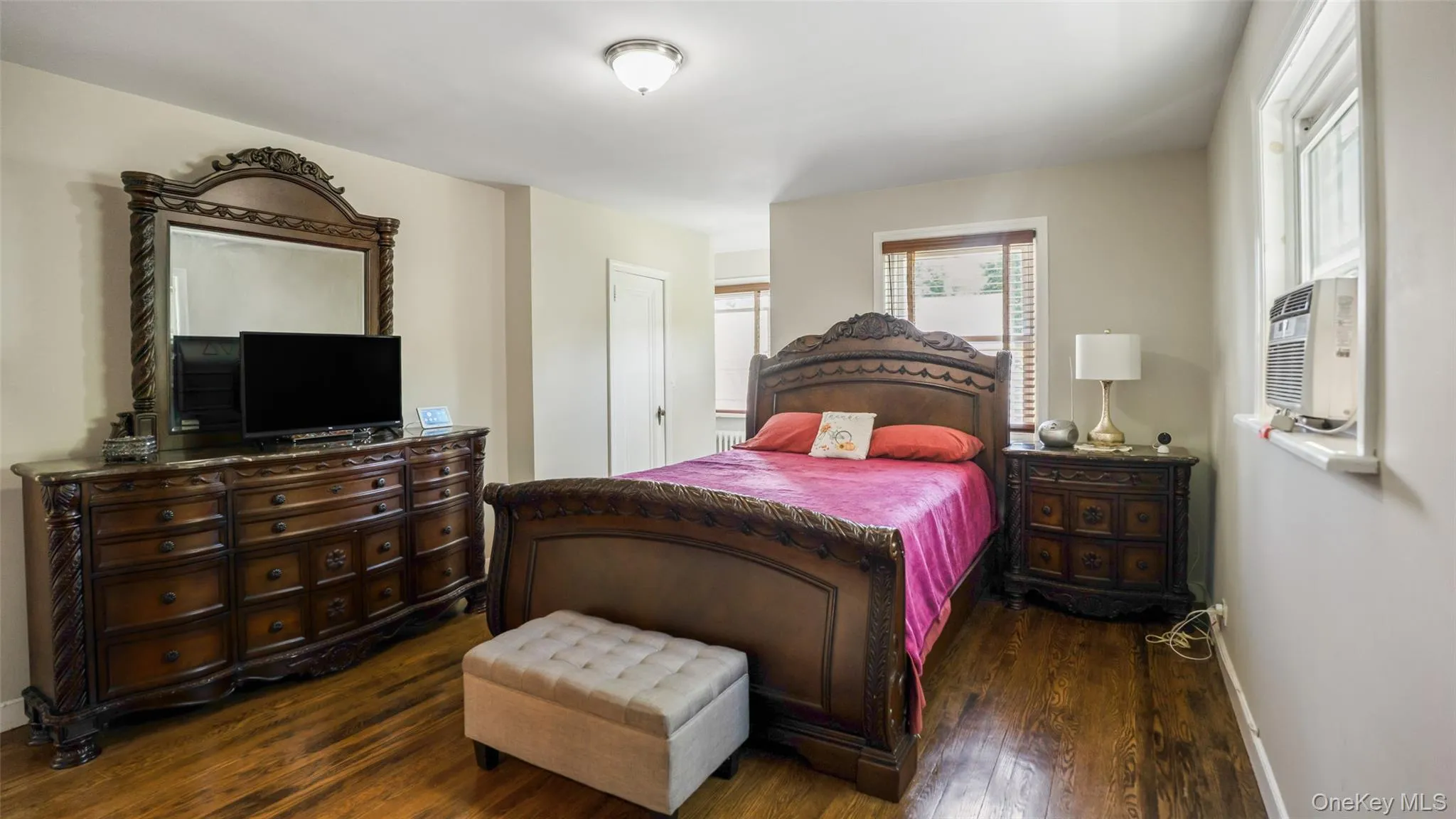 Interior room featuring wood-finish flooring, light-colored wall paint, and a ceiling-mounted light fixture Interior room featuring wood-finish flooring, light-colored wall paint, and a ceiling-mounted light fixture