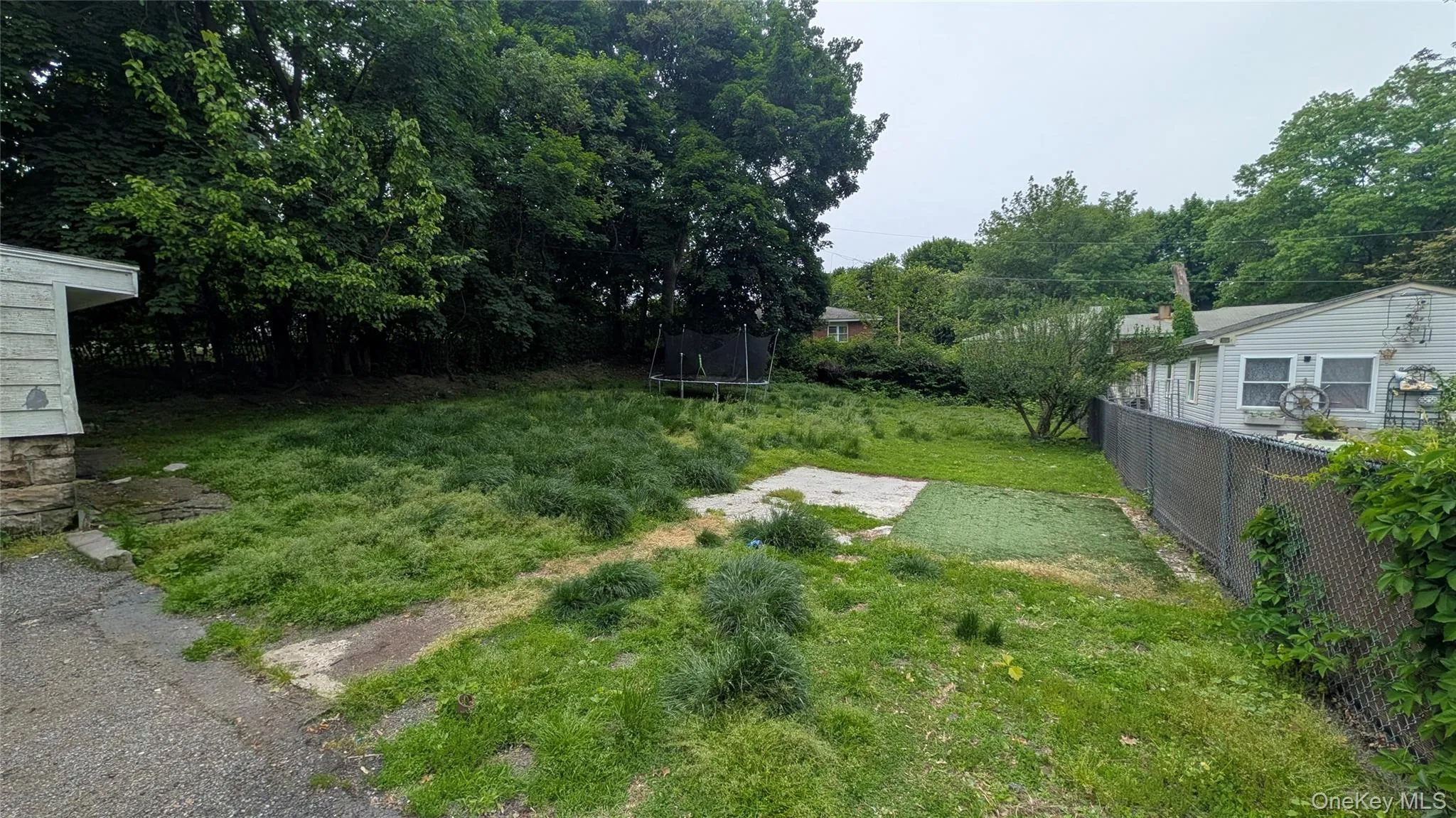 Expansive outdoor space featuring a large grassy area, mature perimeter trees, and a chain-link fence Expansive outdoor space featuring a large grassy area, mature perimeter trees, and a chain-link fence