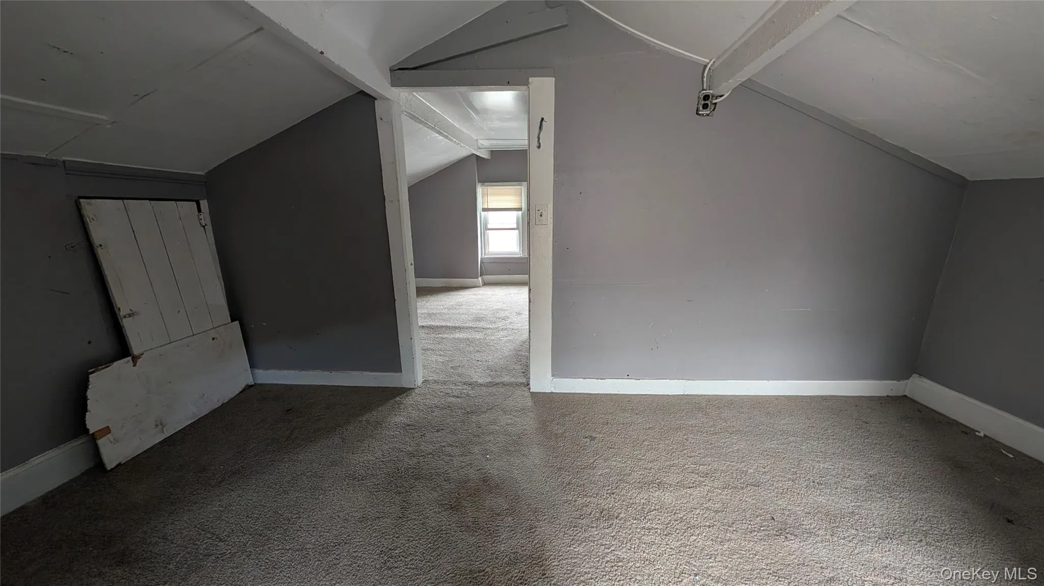 Carpeted attic space with sloped ceilings and painted grey walls Carpeted attic space with sloped ceilings and painted grey walls