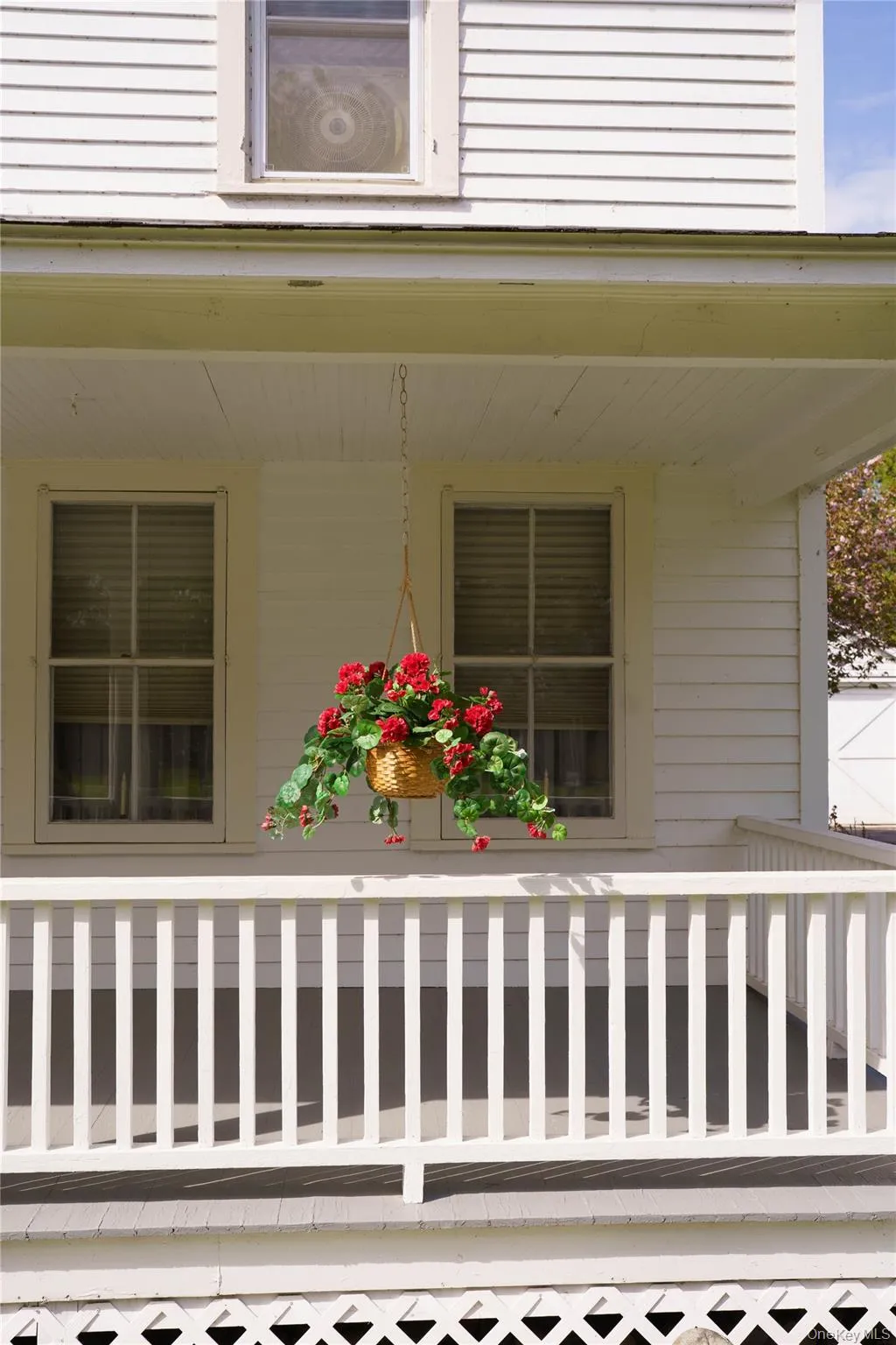 Front porch featuring white siding, a slatted railing, and a lattice foundation skirt Front porch featuring white siding, a slatted railing, and a lattice foundation skirt