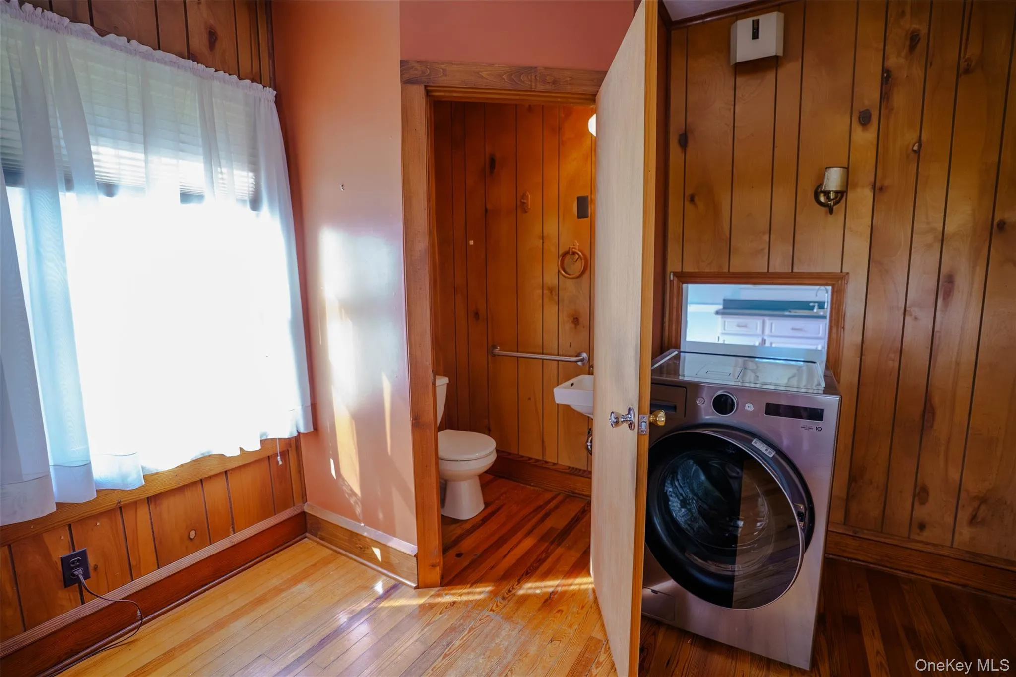 Hardwood flooring with wood paneling walls and trim, featuring a window with blinds Hardwood flooring with wood paneling walls and trim, featuring a window with blinds