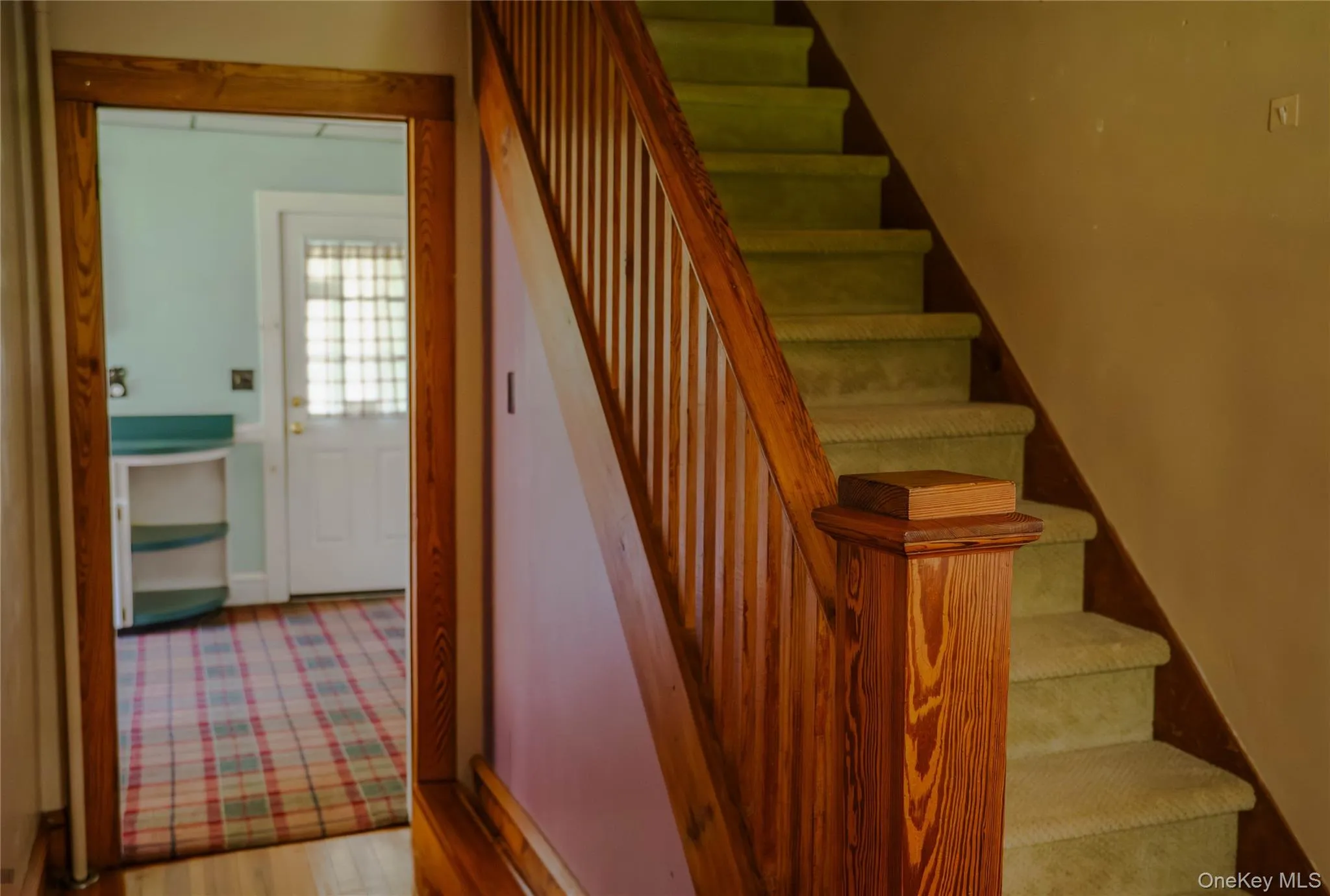 Wood-finish staircase with carpeted treads and a matching wood newel post Wood-finish staircase with carpeted treads and a matching wood newel post