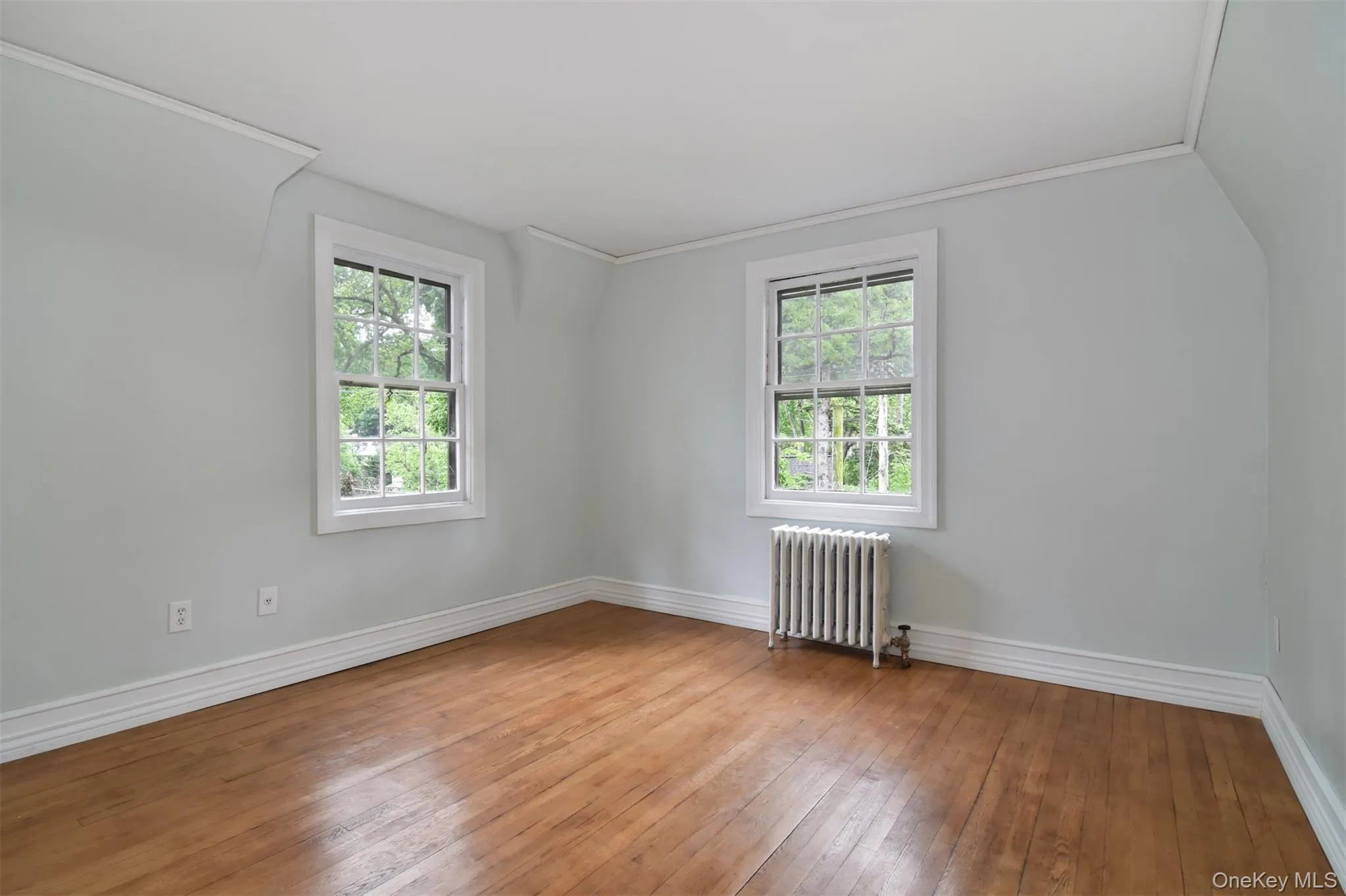 Bedroom featuring rich hardwood flooring, light gray wall paint, and white trim Bedroom featuring rich hardwood flooring, light gray wall paint, and white trim