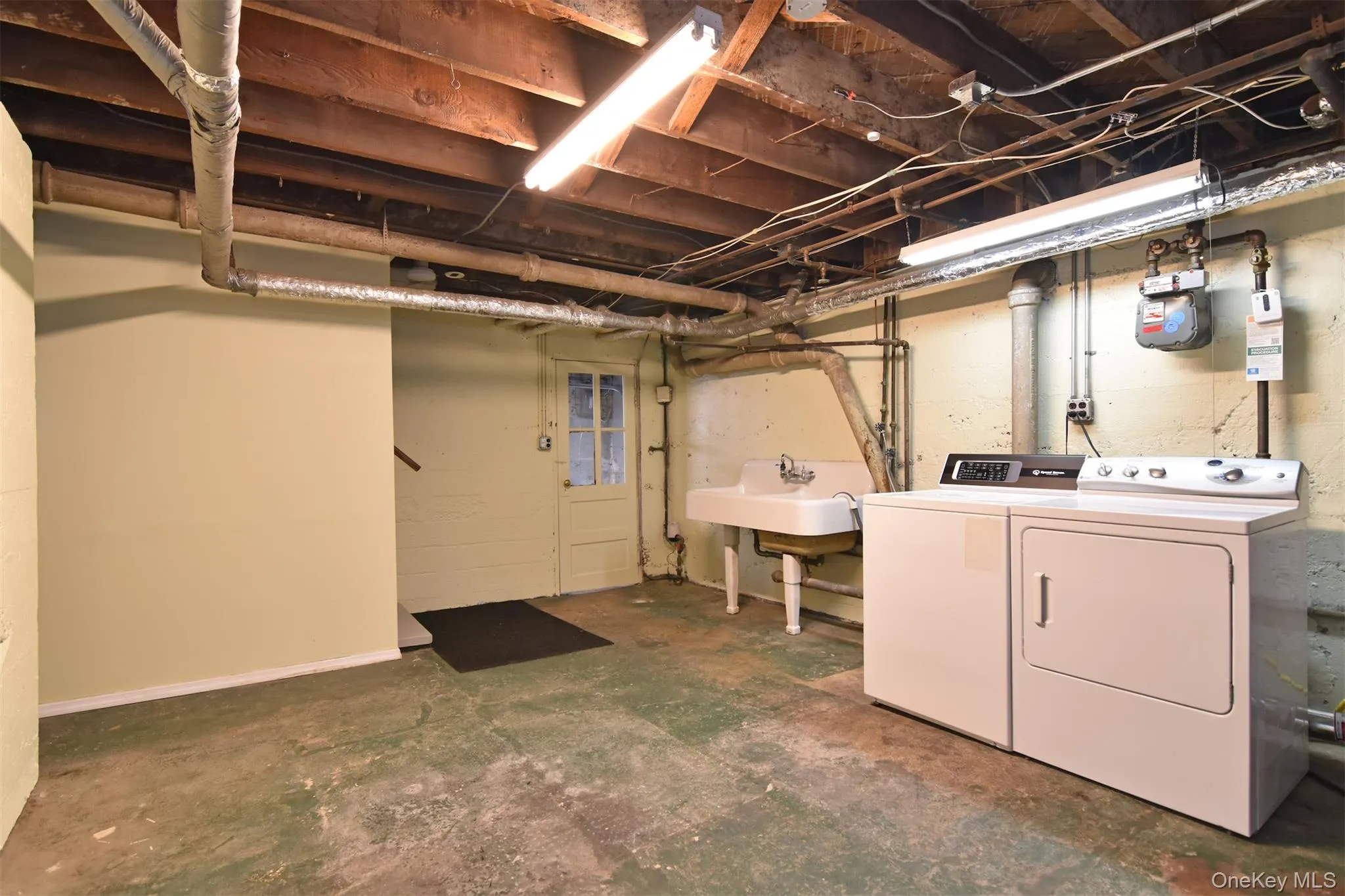 Laundry area featuring a utility sink, washer, and dryer. Office space on opposite wall Laundry area featuring a utility sink, washer, and dryer. Office space on opposite wall