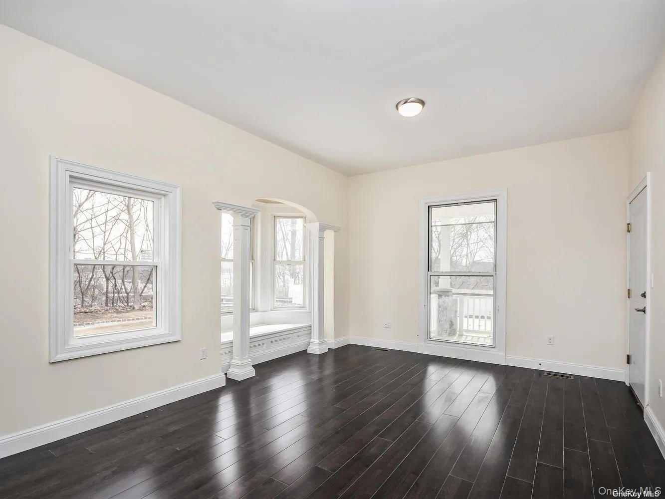 Expansive room featuring dark wood-finish flooring, vaulted ceiling, and multiple windows Expansive room featuring dark wood-finish flooring, vaulted ceiling, and multiple windows
