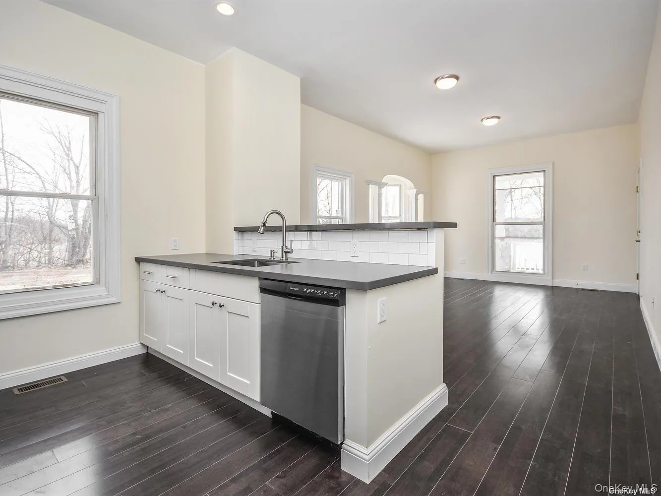 Kitchen island featuring a stainless steel sink with gooseneck faucet, white subway tile backsplash, and dark countertop Kitchen island featuring a stainless steel sink with gooseneck faucet, white subway tile backsplash, and dark countertop