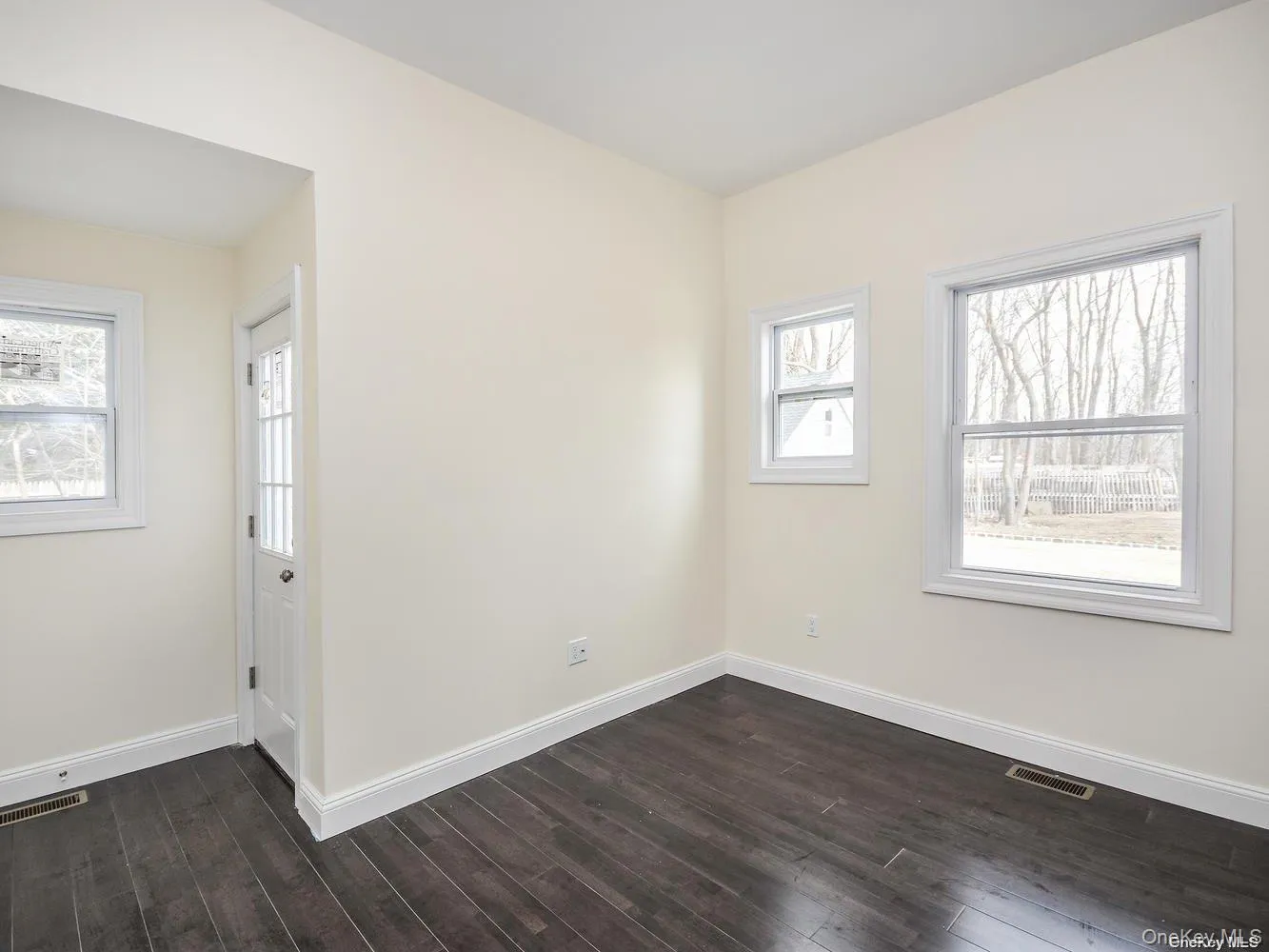 Interior space featuring dark wood-finish flooring and light-toned walls Interior space featuring dark wood-finish flooring and light-toned walls