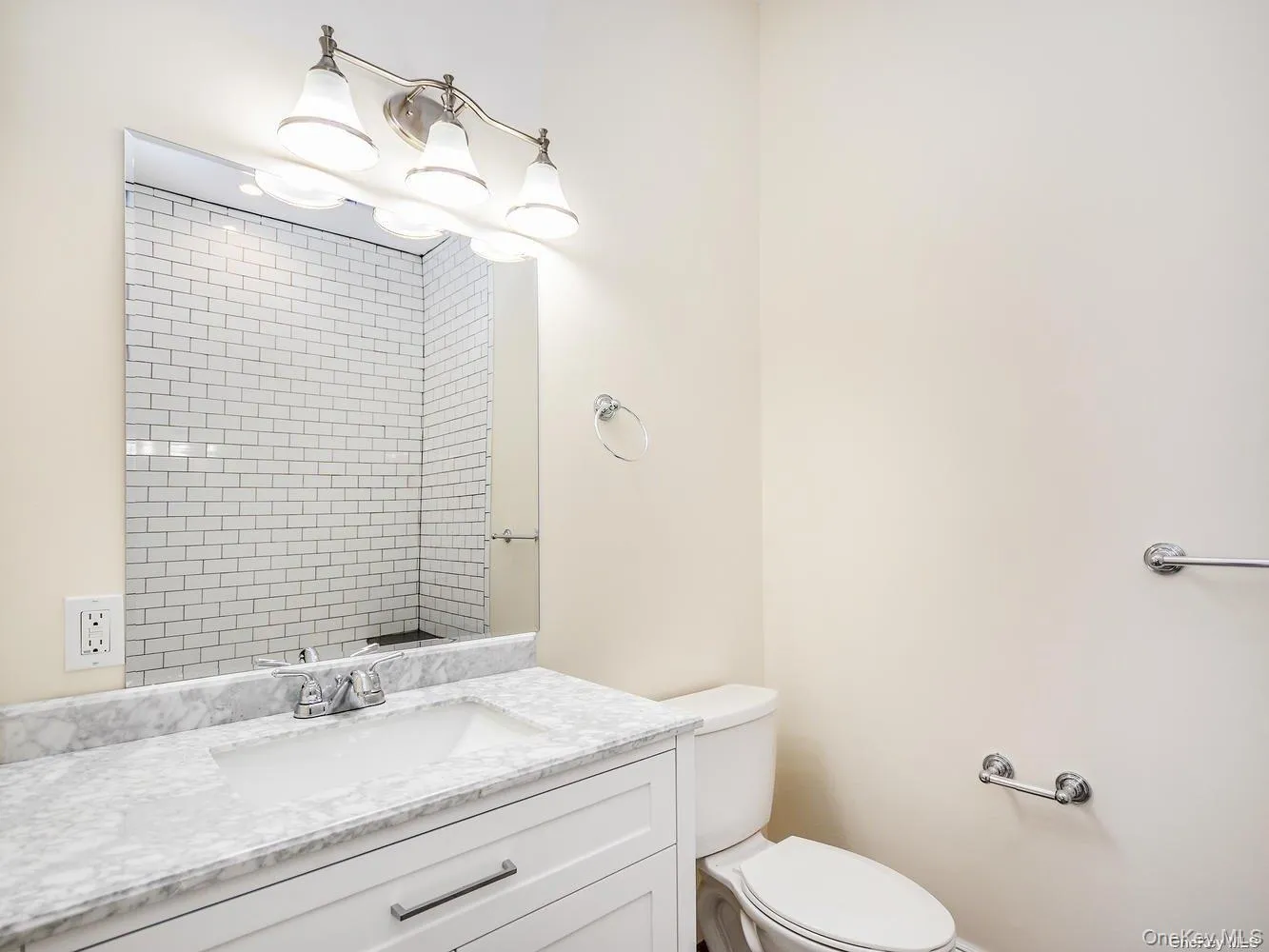 Bathroom featuring a white vanity with an integrated sink, a marble-patterned countertop, and a chrome faucet Bathroom featuring a white vanity with an integrated sink, a marble-patterned countertop, and a chrome faucet