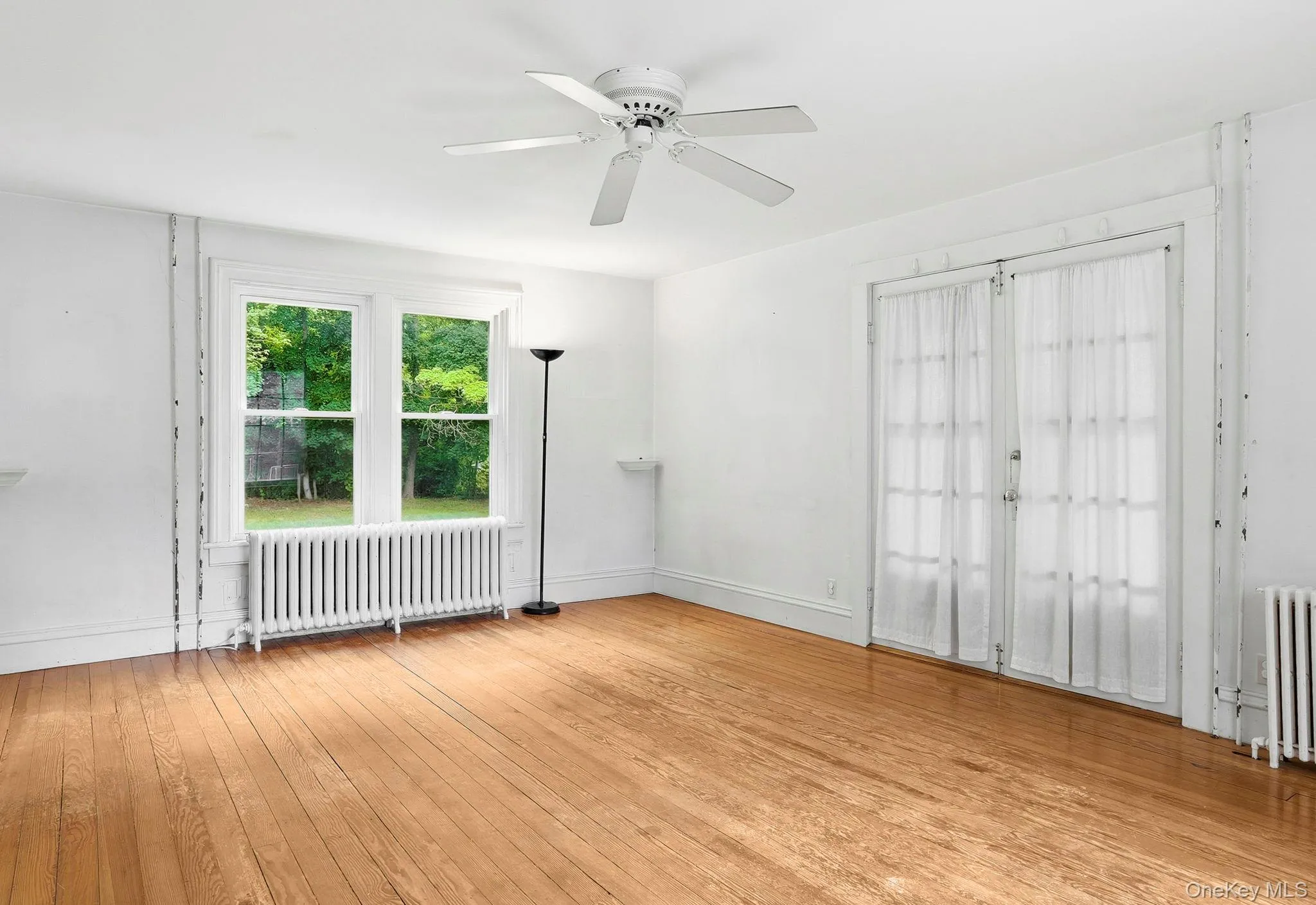 Hardwood flooring featuring a ceiling fan, dual windows, and white baseboards Hardwood flooring featuring a ceiling fan, dual windows, and white baseboards