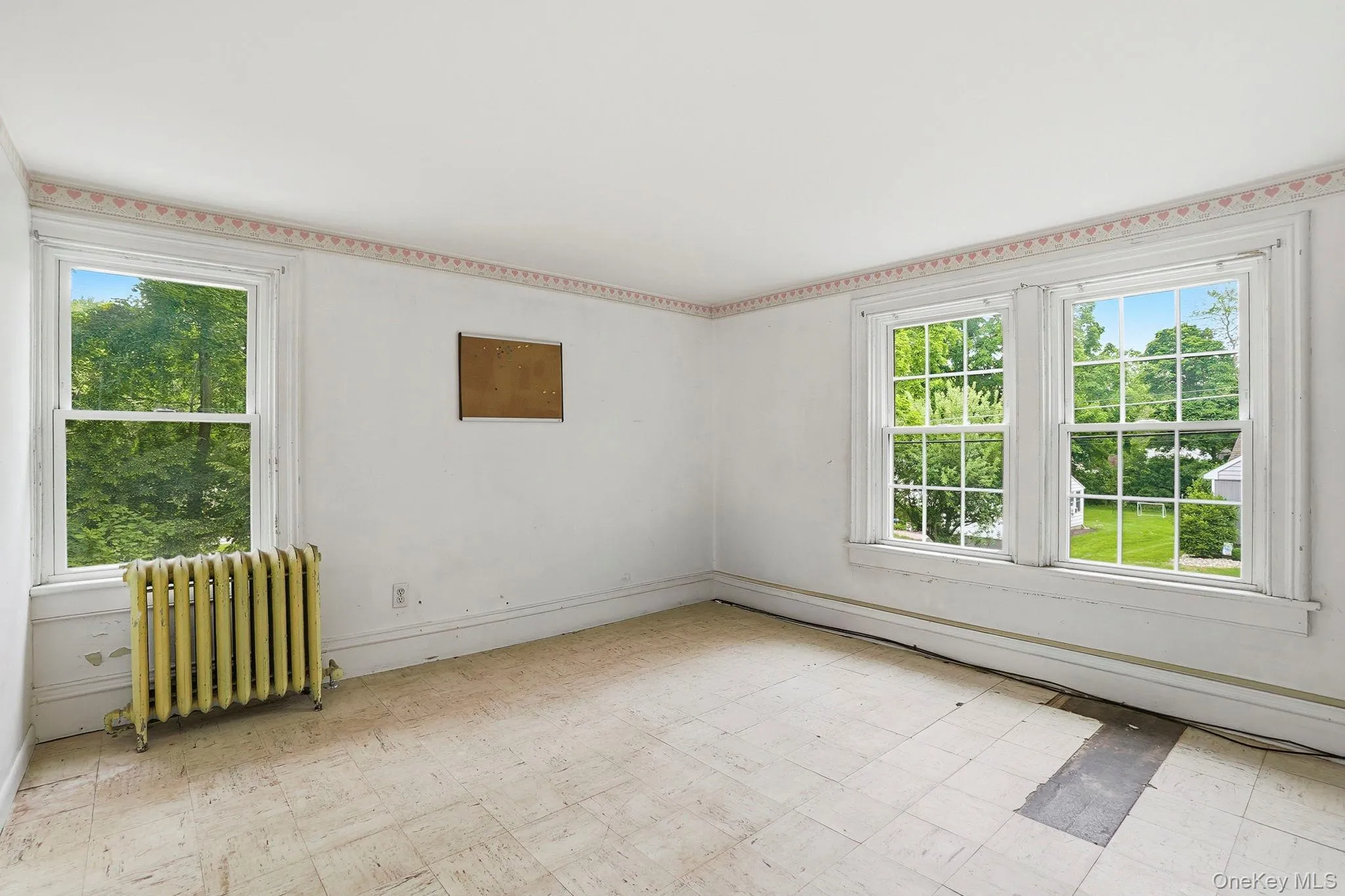 Room featuring multiple windows, a radiator, and a decorative border Room featuring multiple windows, a radiator, and a decorative border