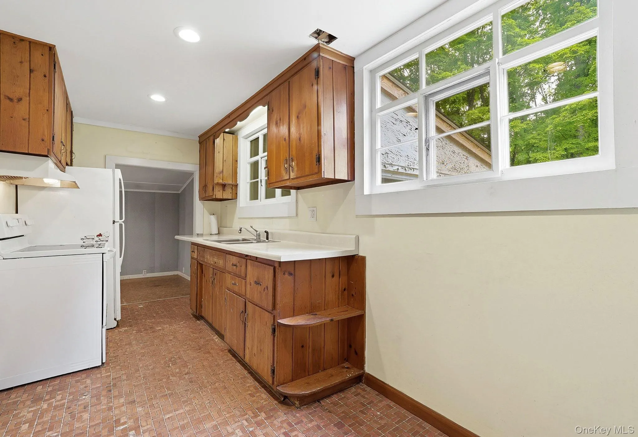 Kitchen featuring wood cabinetry, white countertops, a large window, recessed lighting, and resilient flooring Kitchen featuring wood cabinetry, white countertops, a large window, recessed lighting, and resilient flooring