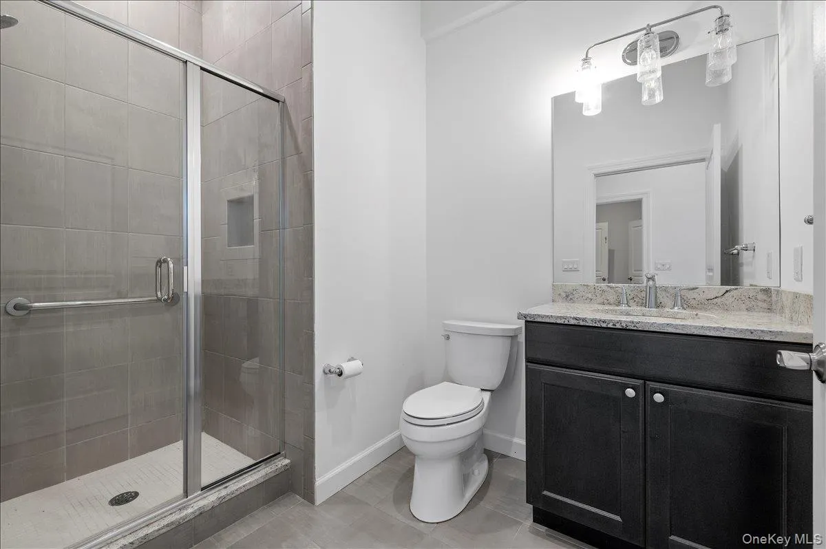 Bathroom featuring a shower stall, vanity, and light tile patterned floors Bathroom featuring a shower stall, vanity, and light tile patterned floors
