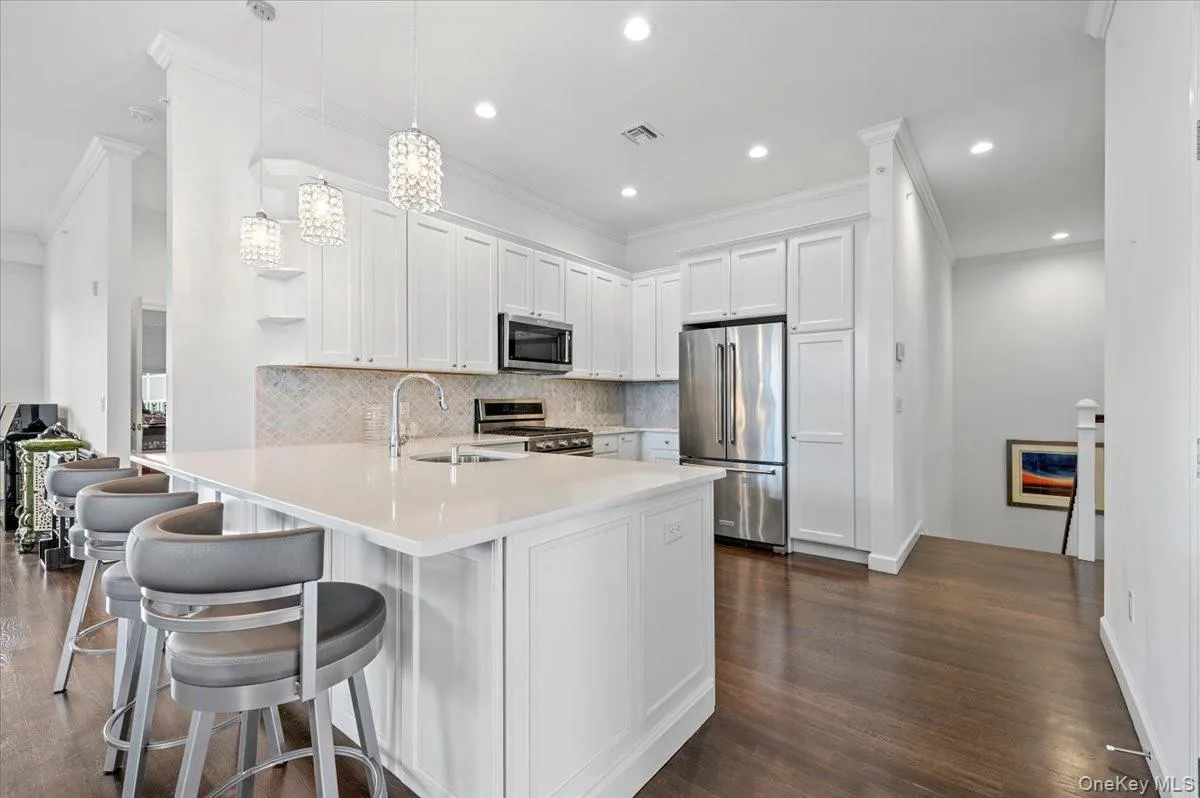 Kitchen featuring open shelves,stainless steel appliances,white cabinetry, decorativebacksplash, and decorativelight fixtures Kitchen featuring open shelves,stainless steel appliances,white cabinetry, decorativebacksplash, and decorativelight fixtures