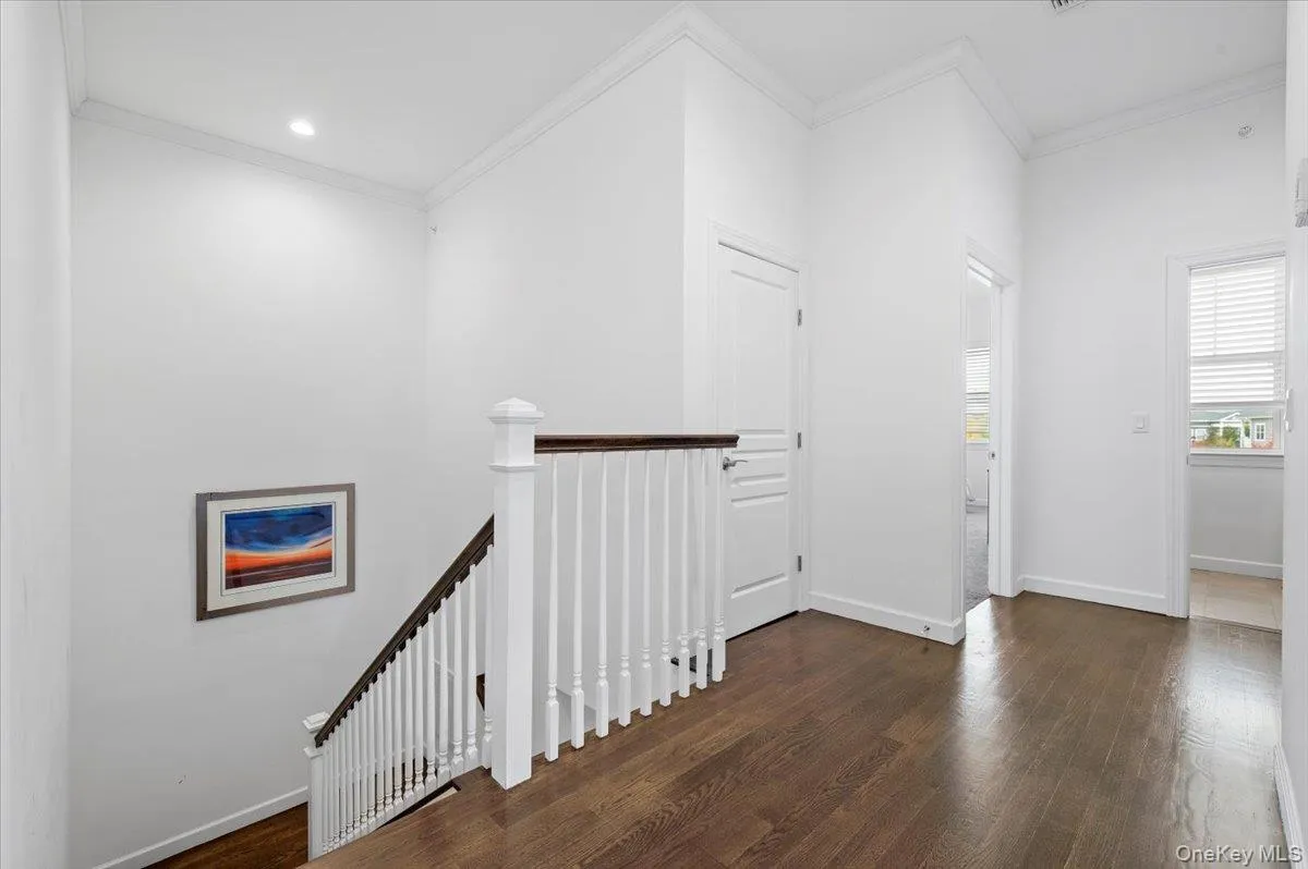 Hallway with an upstairslanding, ornamental molding,dark wood-type flooring, andrecessed lighting Hallway with an upstairslanding, ornamental molding,dark wood-type flooring, andrecessed lighting