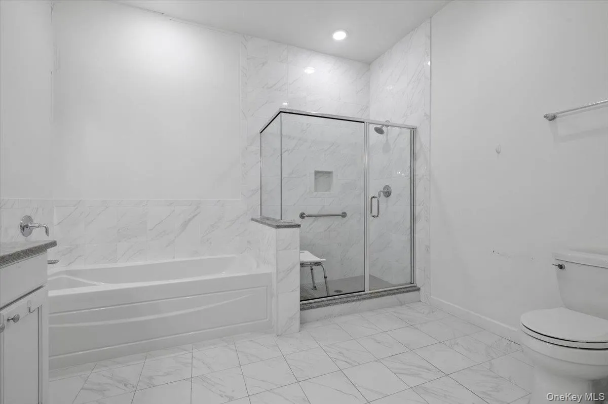 Full bathroom featuring vanity,a marble finish shower, a garden tub, and light marble finish floorin Full bathroom featuring vanity,a marble finish shower, a garden tub, and light marble finish floorin