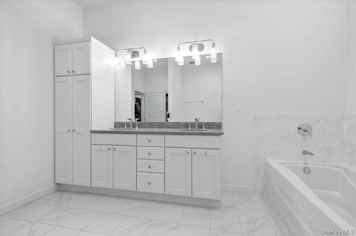 Bathroom featuring double vanity, a garden tub, and lightmarble finish flooring Bathroom featuring double vanity, a garden tub, and lightmarble finish flooring