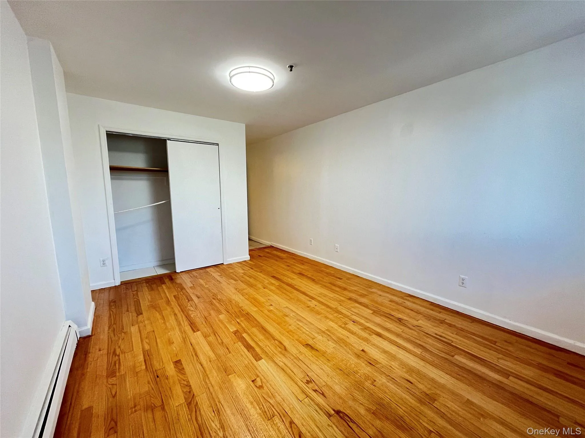 Hardwood flooring throughout featuring a built-in closet with sliding doors and interior shelving Hardwood flooring throughout featuring a built-in closet with sliding doors and interior shelving