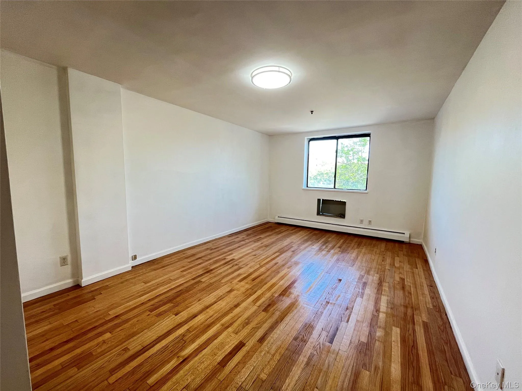 Spacious room featuring wood-finish flooring with sliding doors. Spacious room featuring wood-finish flooring with sliding doors.