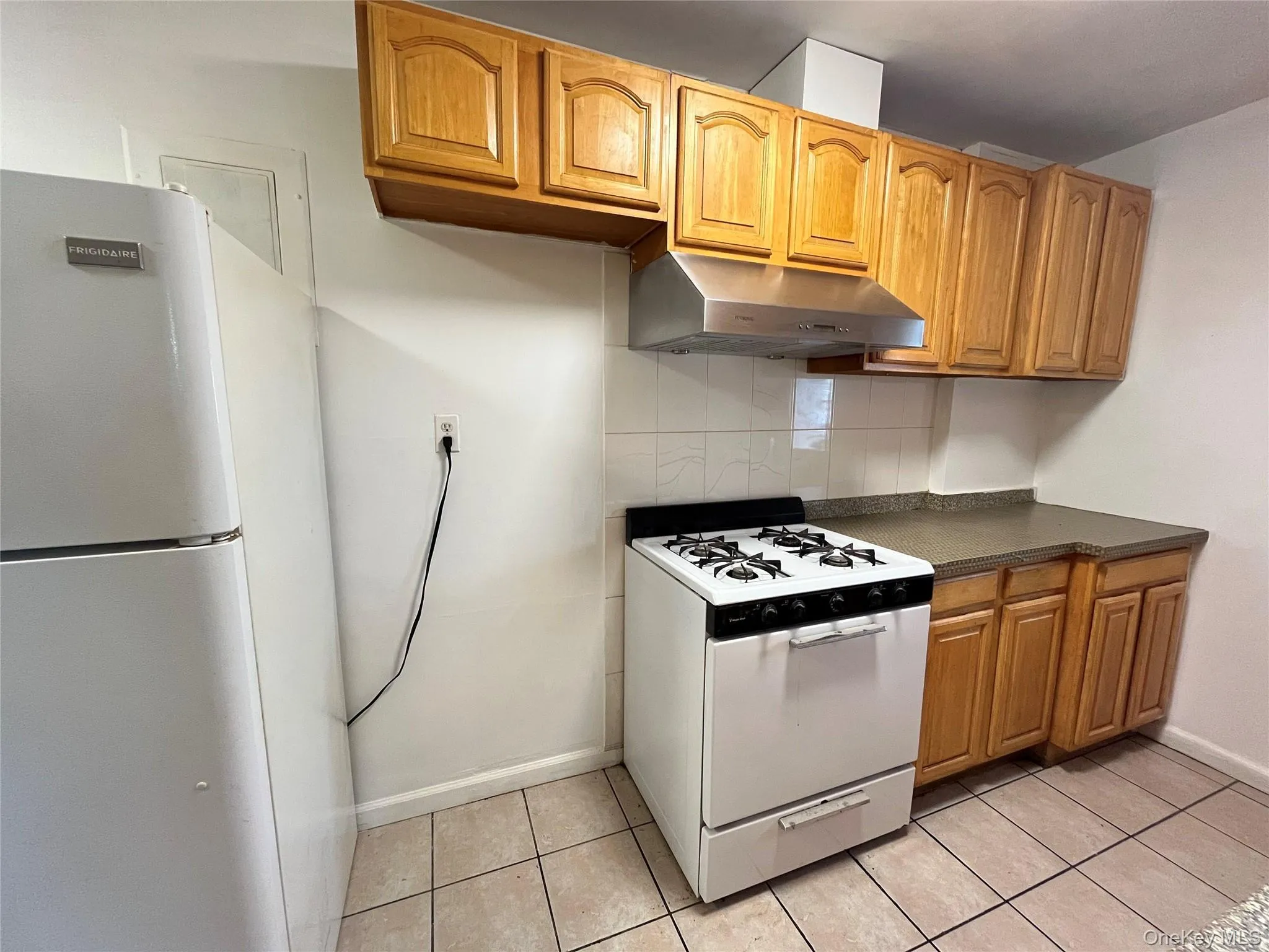 Kitchen featuring light wood-finish cabinetry, and white tile backsplash. Kitchen featuring light wood-finish cabinetry, and white tile backsplash.
