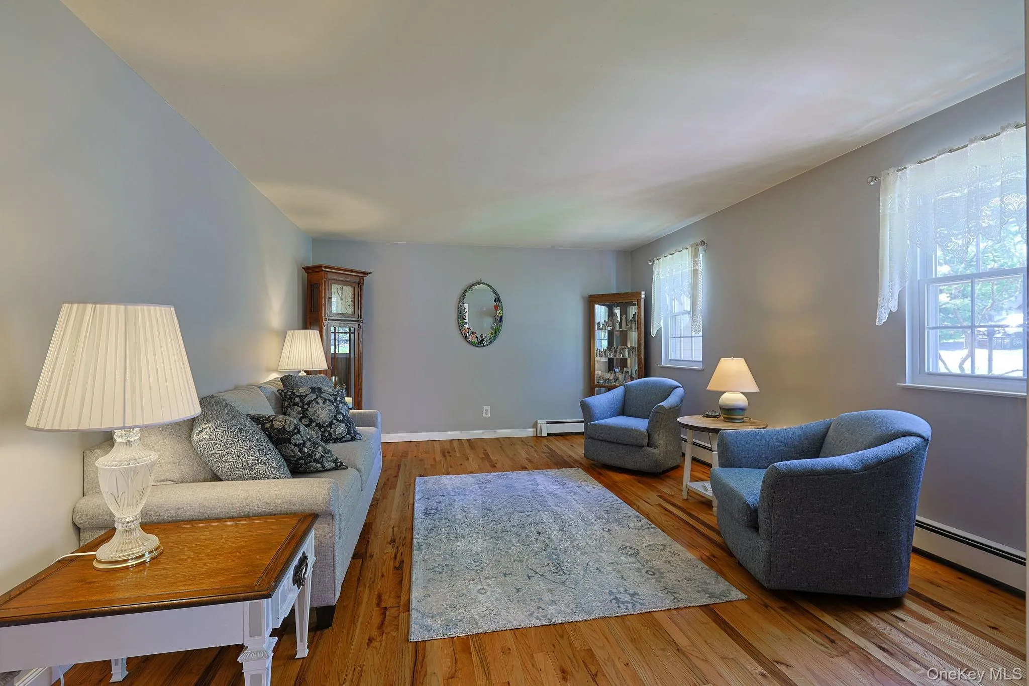 Bright living space featuring hardwood flooring, light gray wall tones, baseboard trim, and multiple windows Bright living space featuring hardwood flooring, light gray wall tones, baseboard trim, and multiple windows