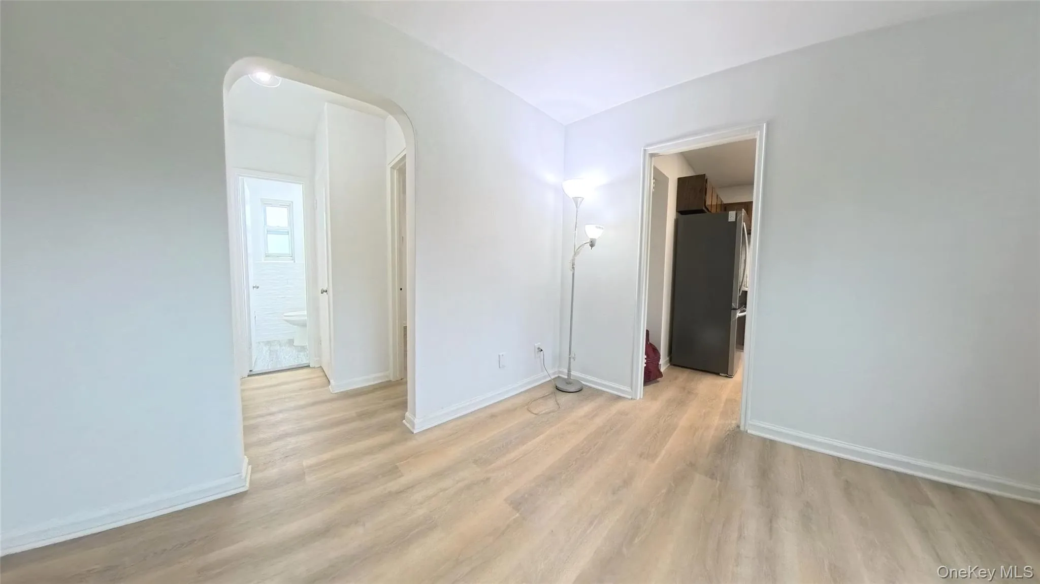 Spare room with light wood-type flooring, baseboards, and arched walkways Spare room with light wood-type flooring, baseboards, and arched walkways