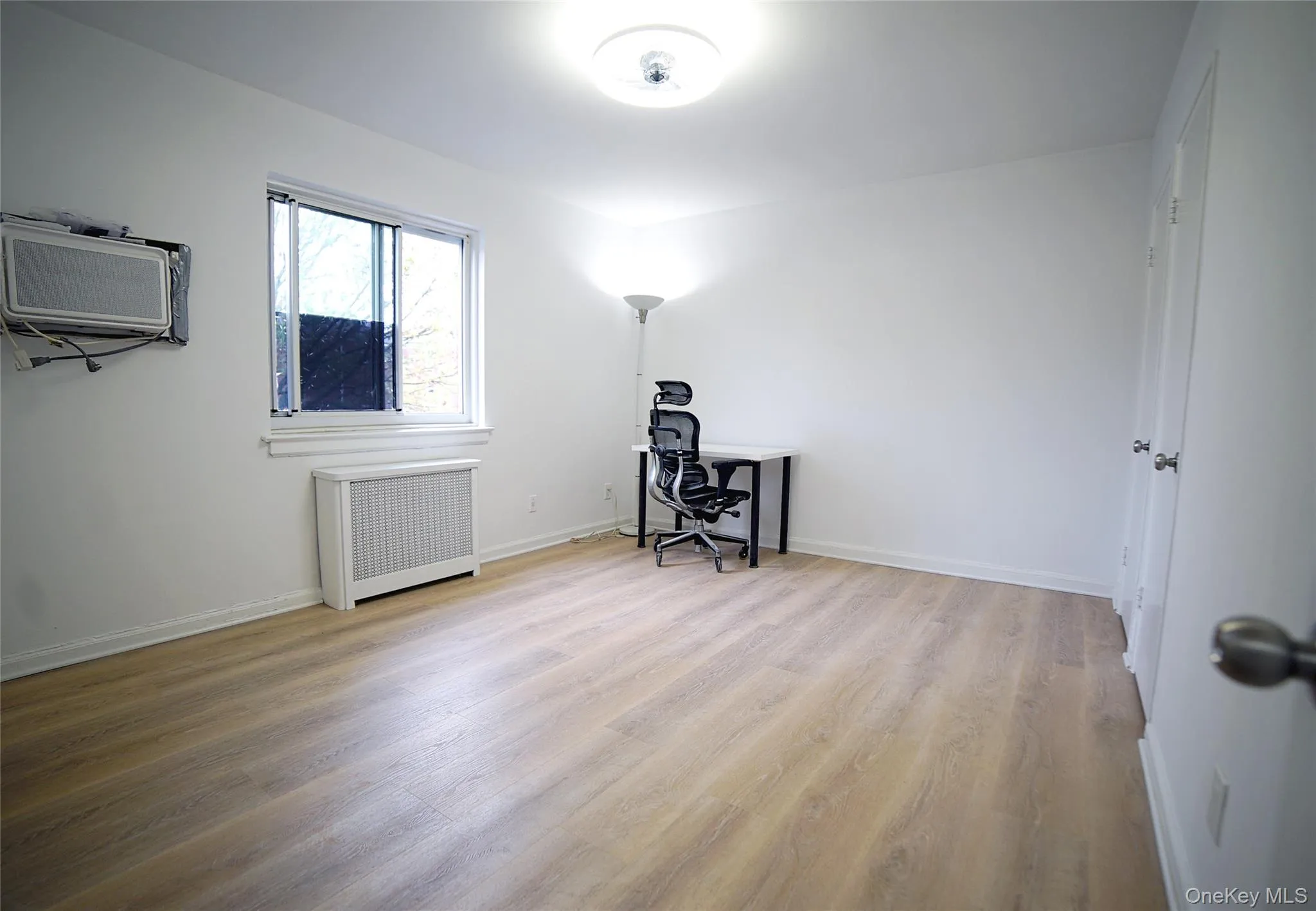 Office space with wood finished floors, baseboards, and radiator heating unit Office space with wood finished floors, baseboards, and radiator heating unit