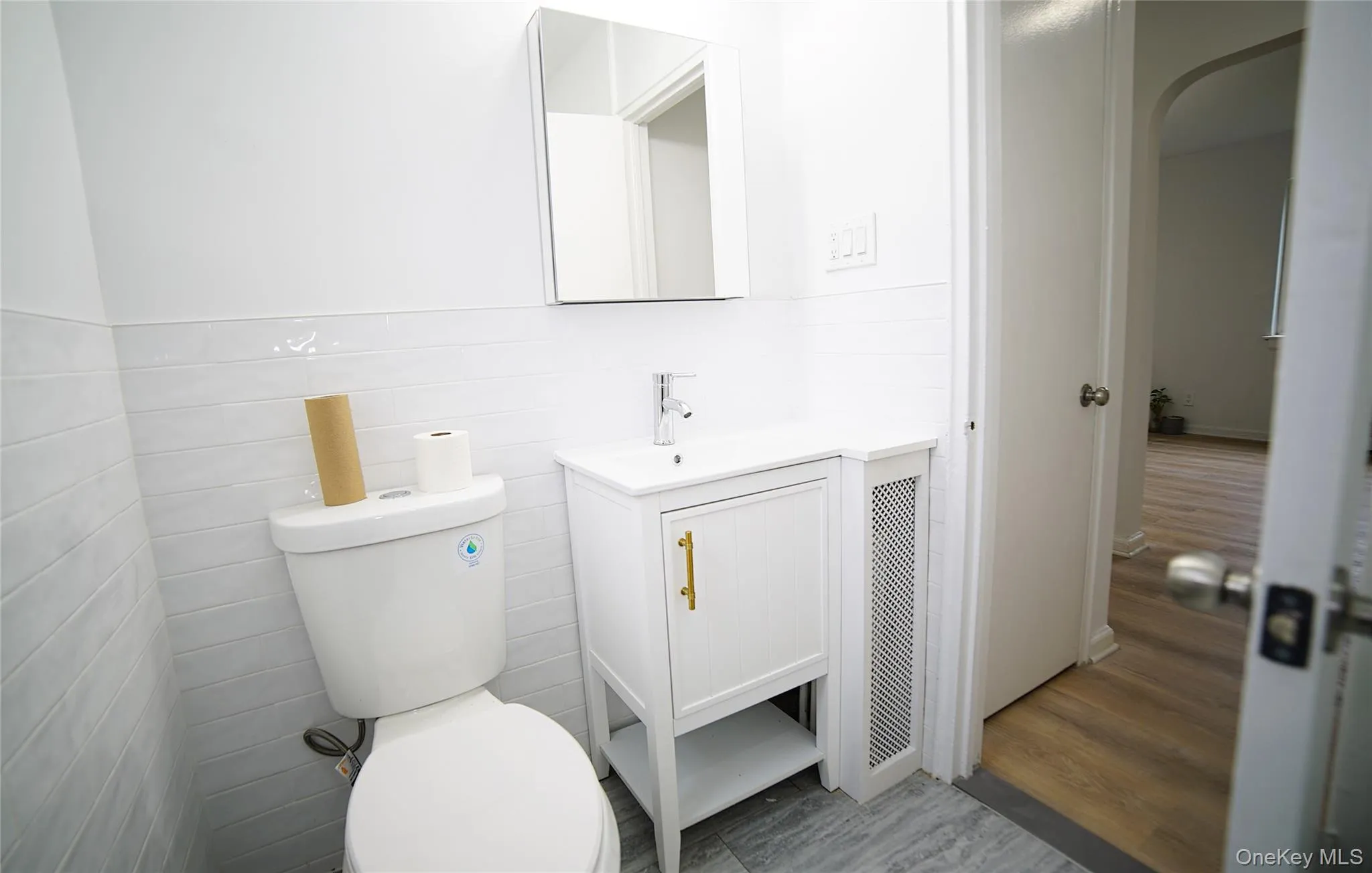 Half bath featuring vanity, toilet, and wood finished floors Half bath featuring vanity, toilet, and wood finished floors