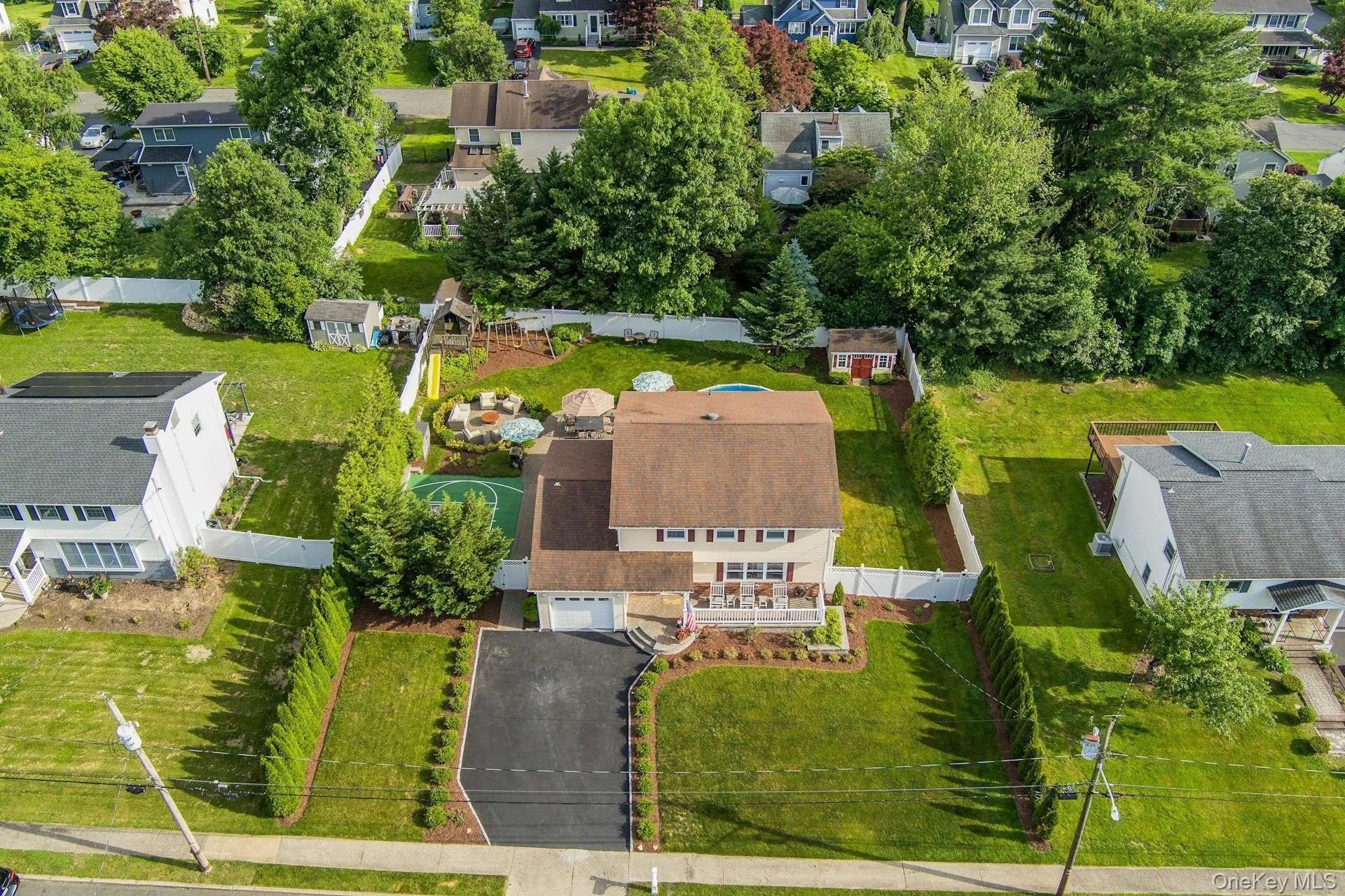Expansive property with a paved driveway, front lawn, and established green landscaping Expansive property with a paved driveway, front lawn, and established green landscaping