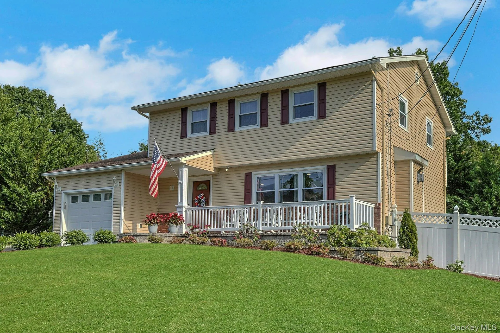 Two-story residence featuring light beige siding and a welcoming front porch with white railings Two-story residence featuring light beige siding and a welcoming front porch with white railings