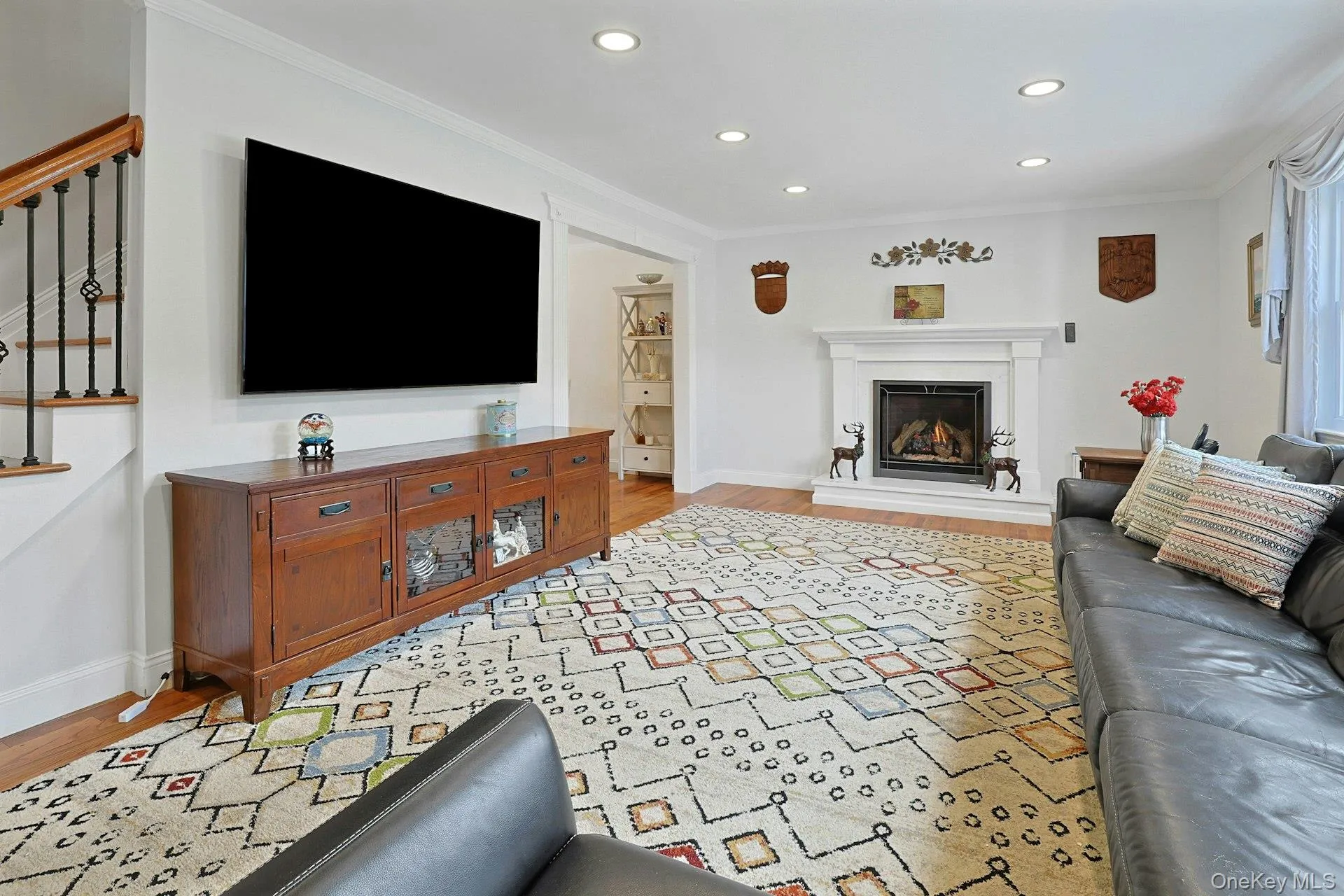 Living area featuring a fireplace with a white mantel, recessed lighting, and wood-finish flooring Living area featuring a fireplace with a white mantel, recessed lighting, and wood-finish flooring