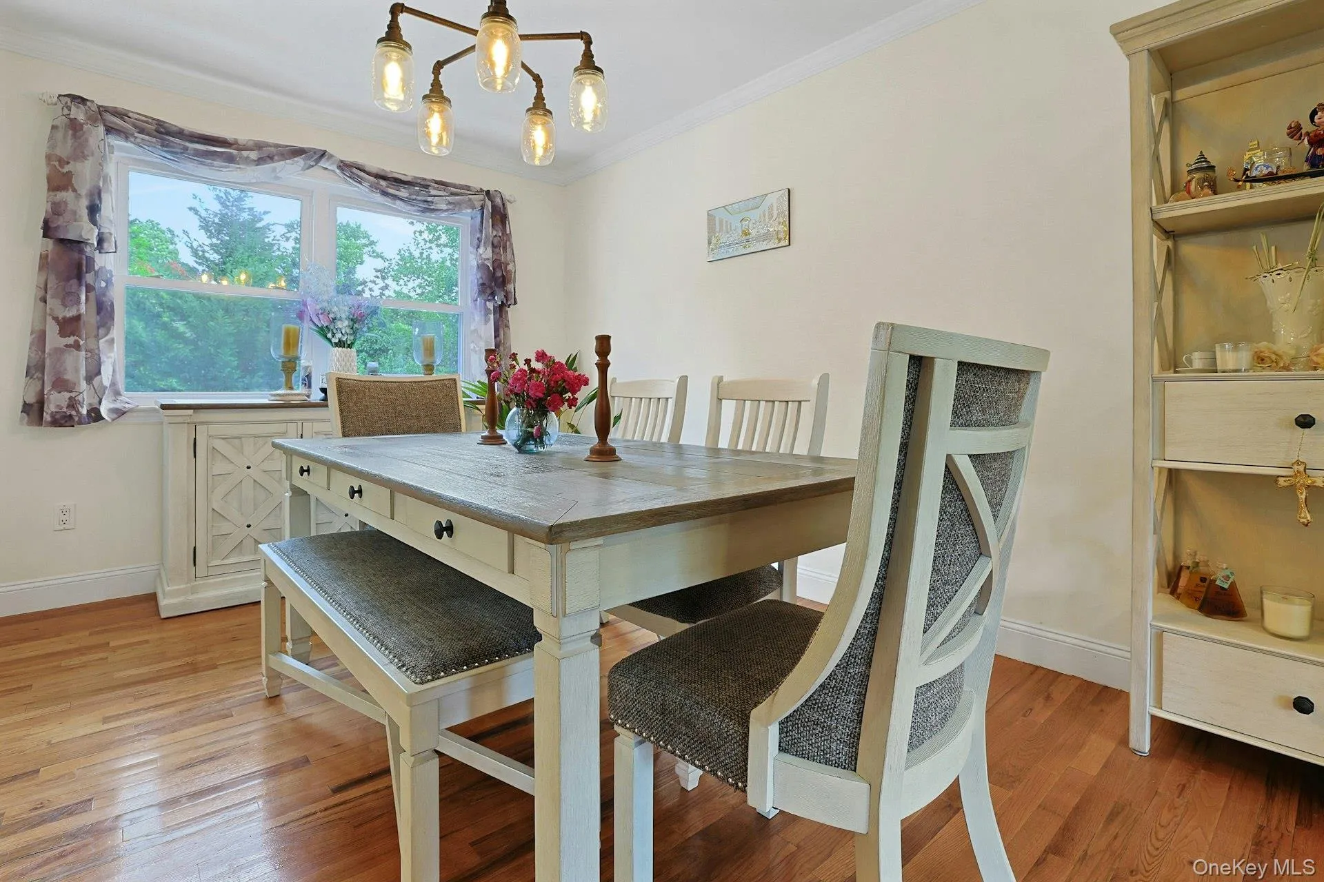Dining area featuring wood-finish flooring, a multi-light chandelier, crown molding, and a built-in shelving unit Dining area featuring wood-finish flooring, a multi-light chandelier, crown molding, and a built-in shelving unit