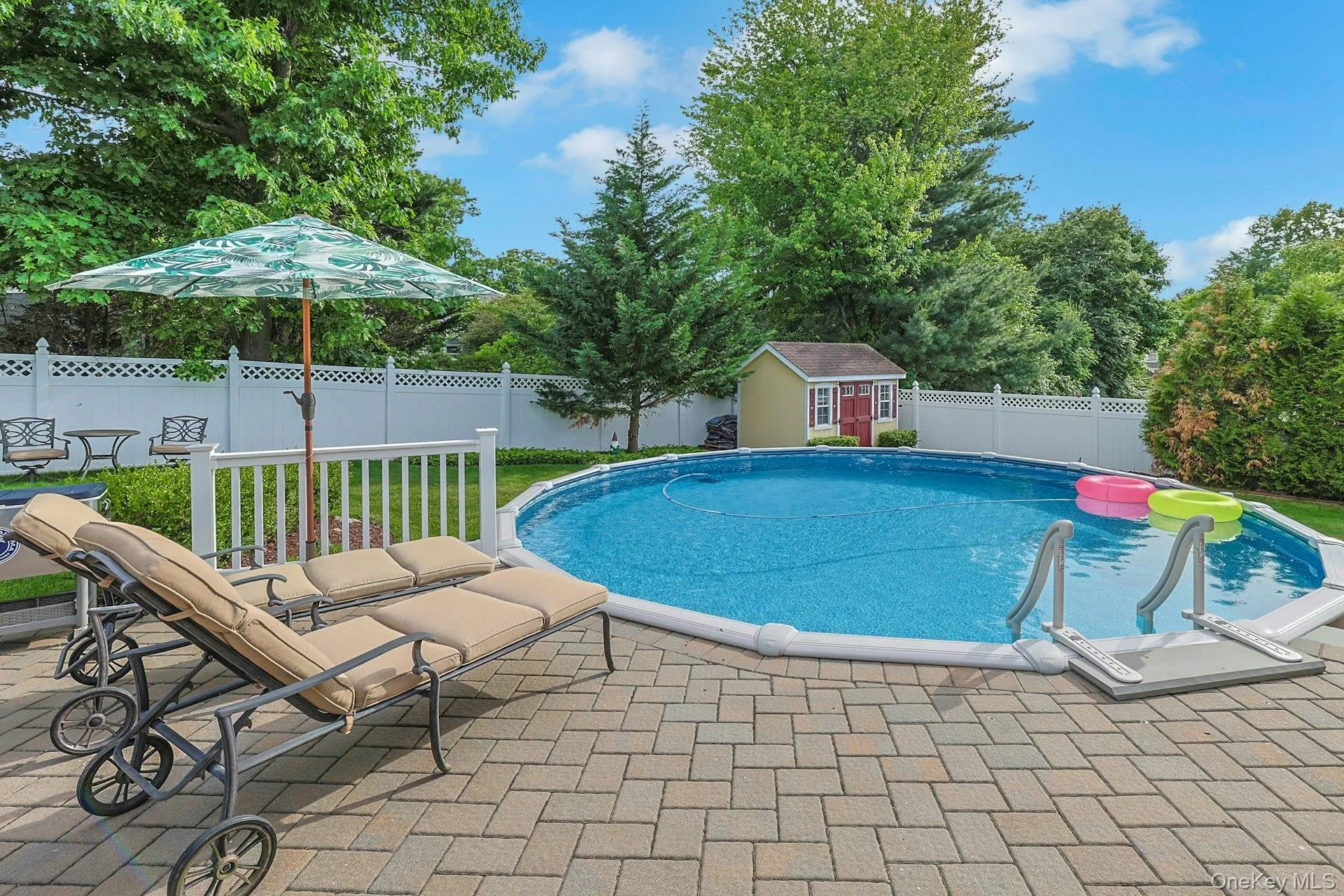 Backyard featuring a round above-ground heated pool with entry steps, complemented by a surrounding paver patio Backyard featuring a round above-ground heated pool with entry steps, complemented by a surrounding paver patio