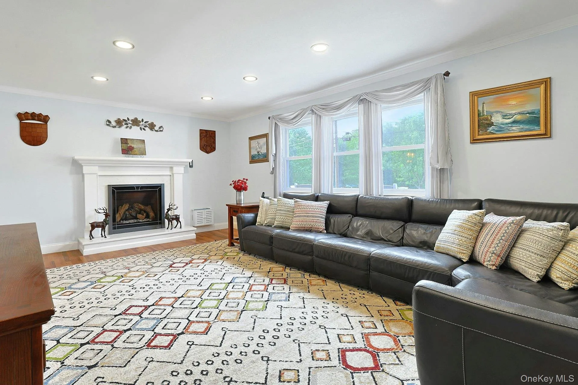 Recessed lighting illuminates this living space featuring a white mantel fireplace with a dark firebox Recessed lighting illuminates this living space featuring a white mantel fireplace with a dark firebox