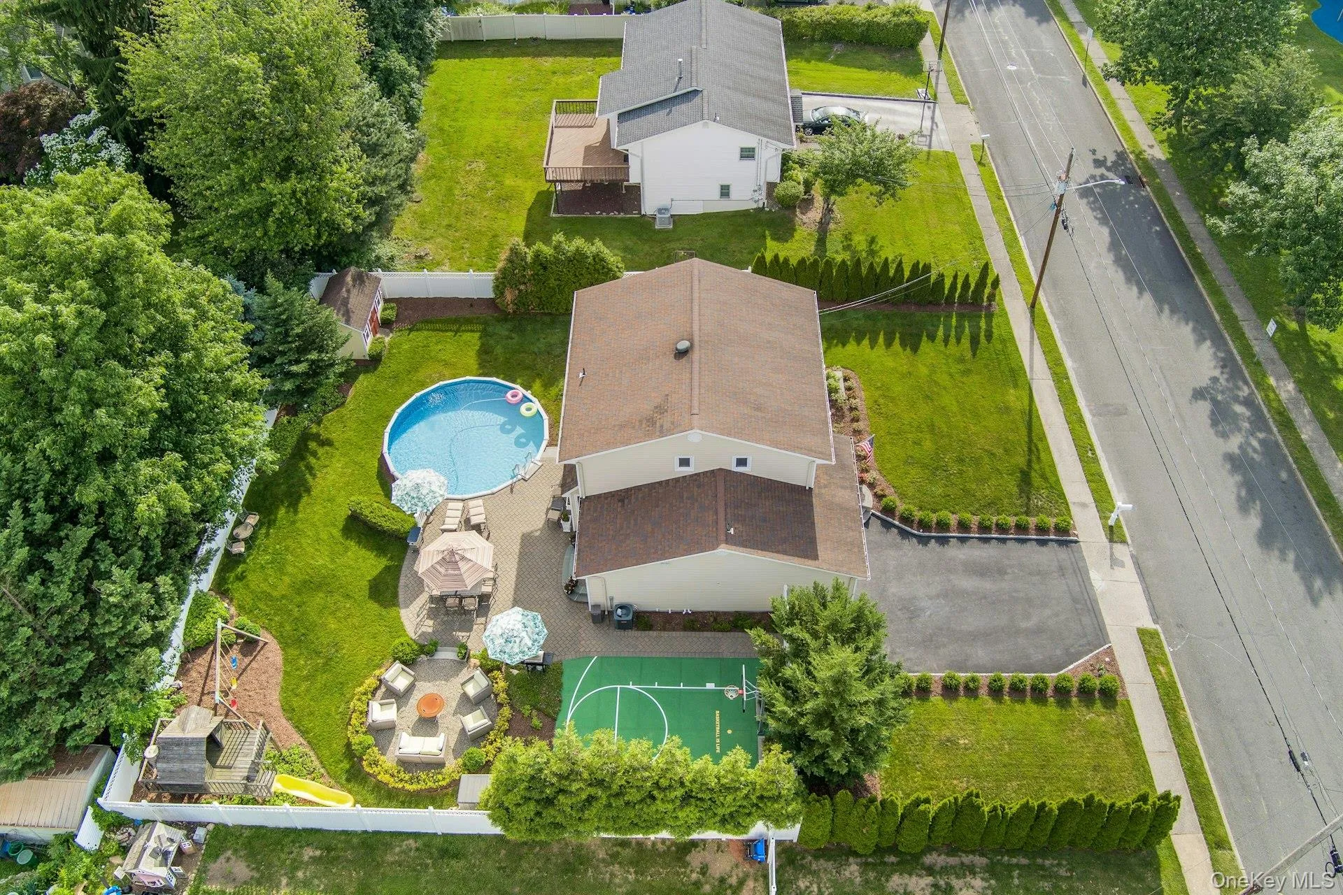 Expansive backyard featuring an above-ground heated pool, paved patio, and a dedicated sports court Expansive backyard featuring an above-ground heated pool, paved patio, and a dedicated sports court